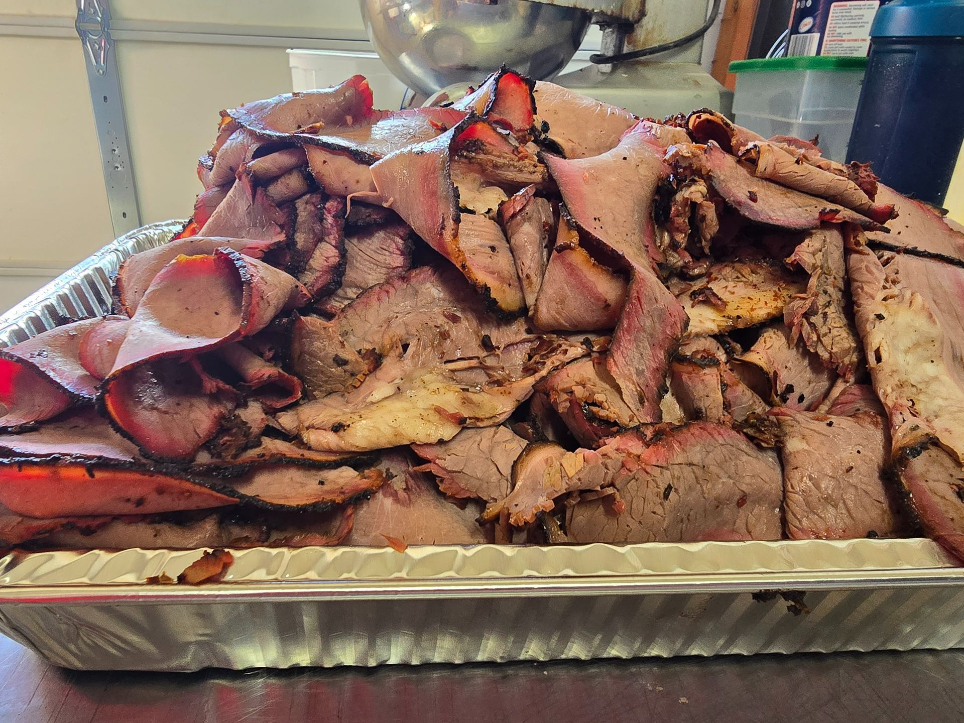Tray piled high with sliced roasted meat and a serving fork on a table