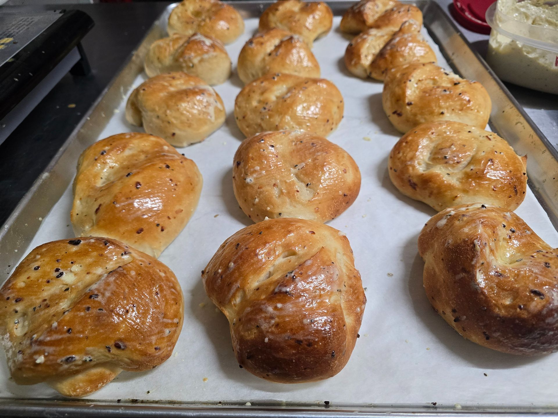 Tray of freshly baked golden-brown bread rolls on parchment paper