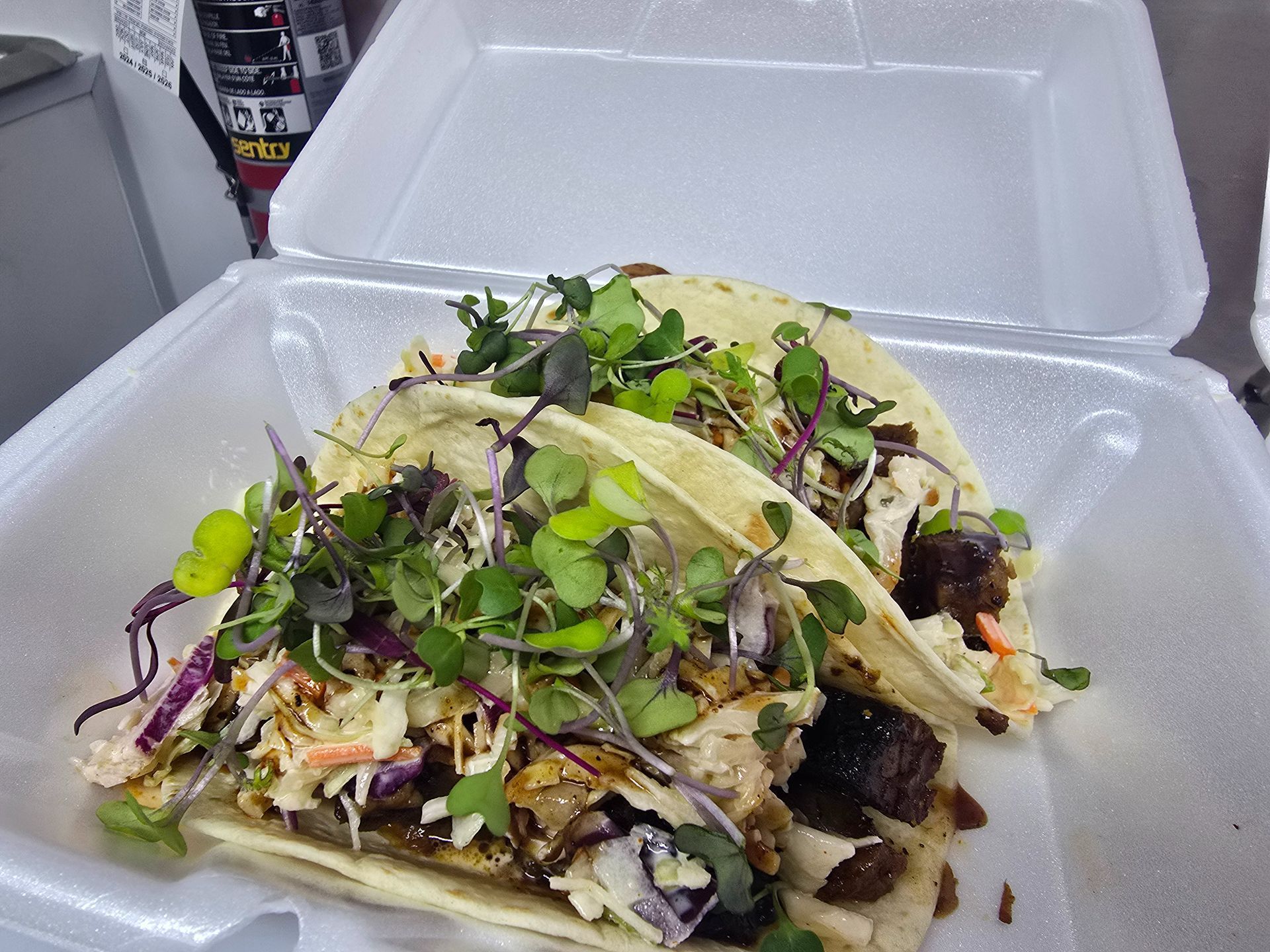 Takeout container of mixed salad with greens, shredded cabbage, and herbs