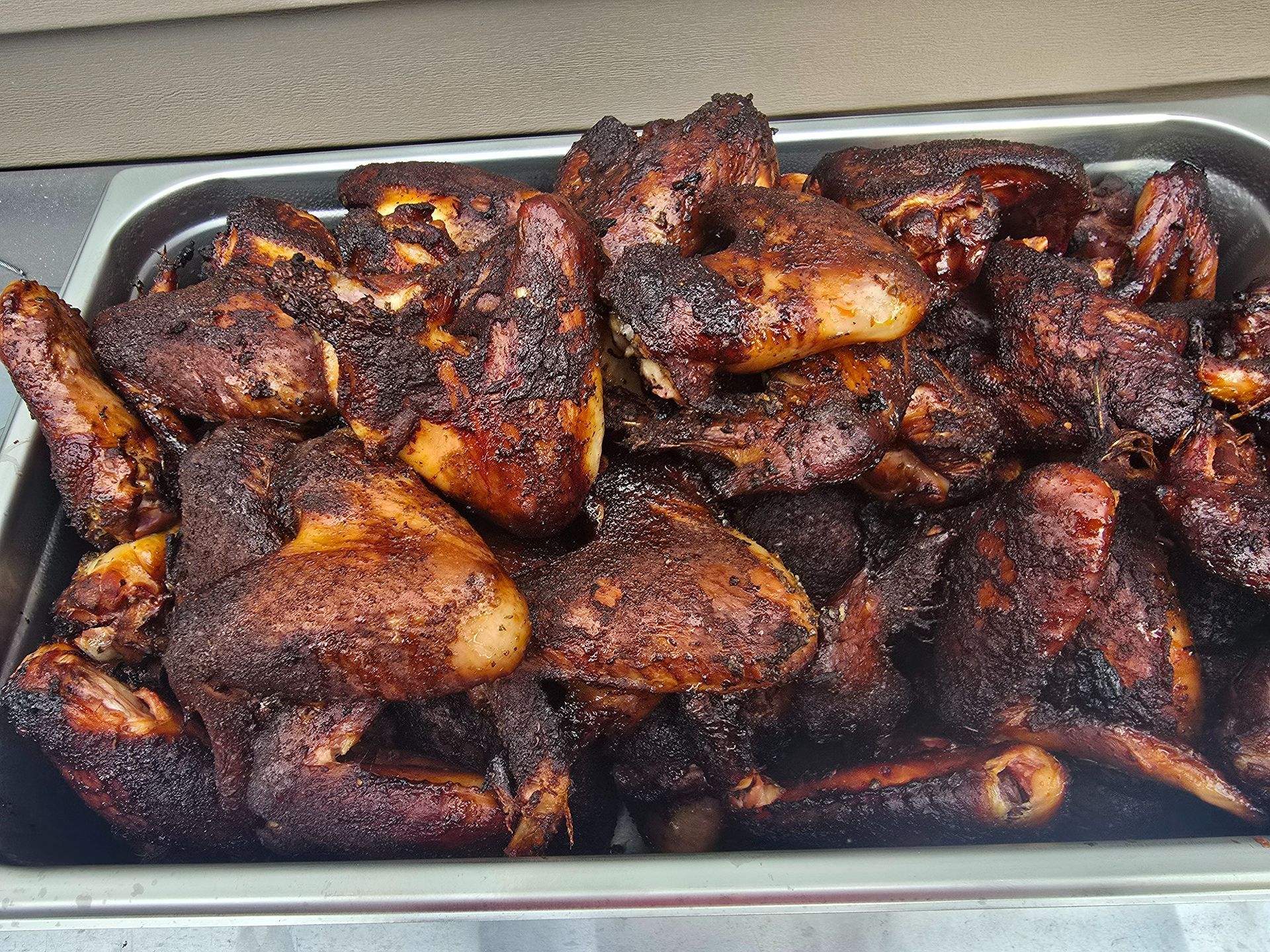 Tray of grilled chicken wings with dark crispy seasoning and charred edges