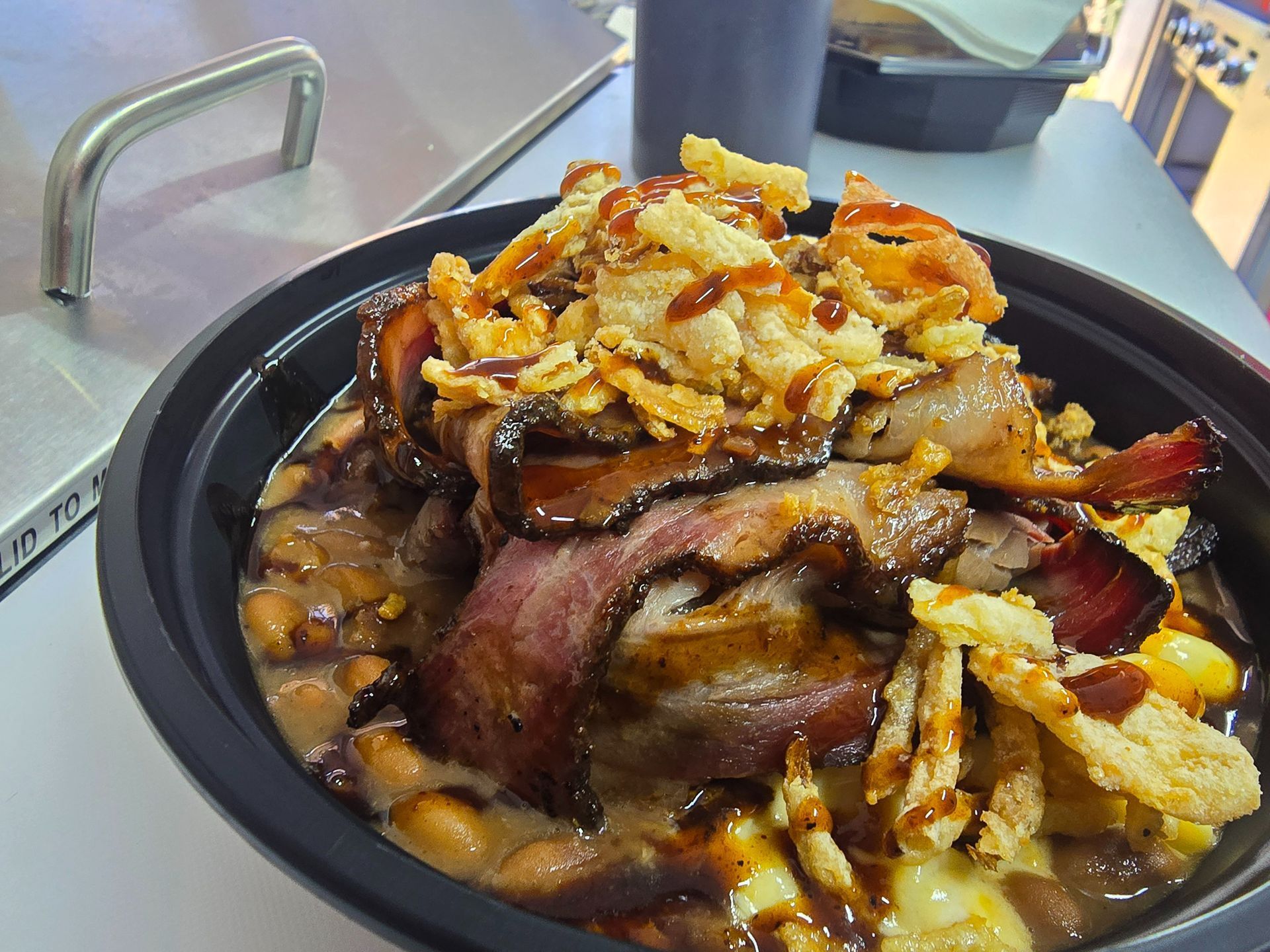 Plate of layered roasted meat topped with crispy onions on a table
