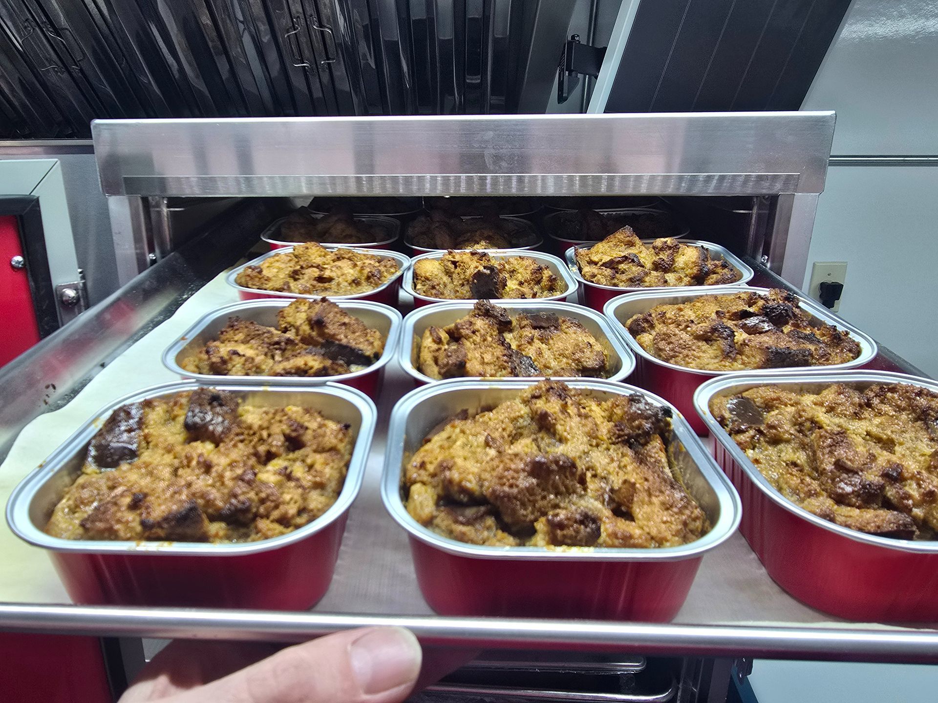 Trays of baked pasta casserole in a buffet warmer, with golden browned tops.