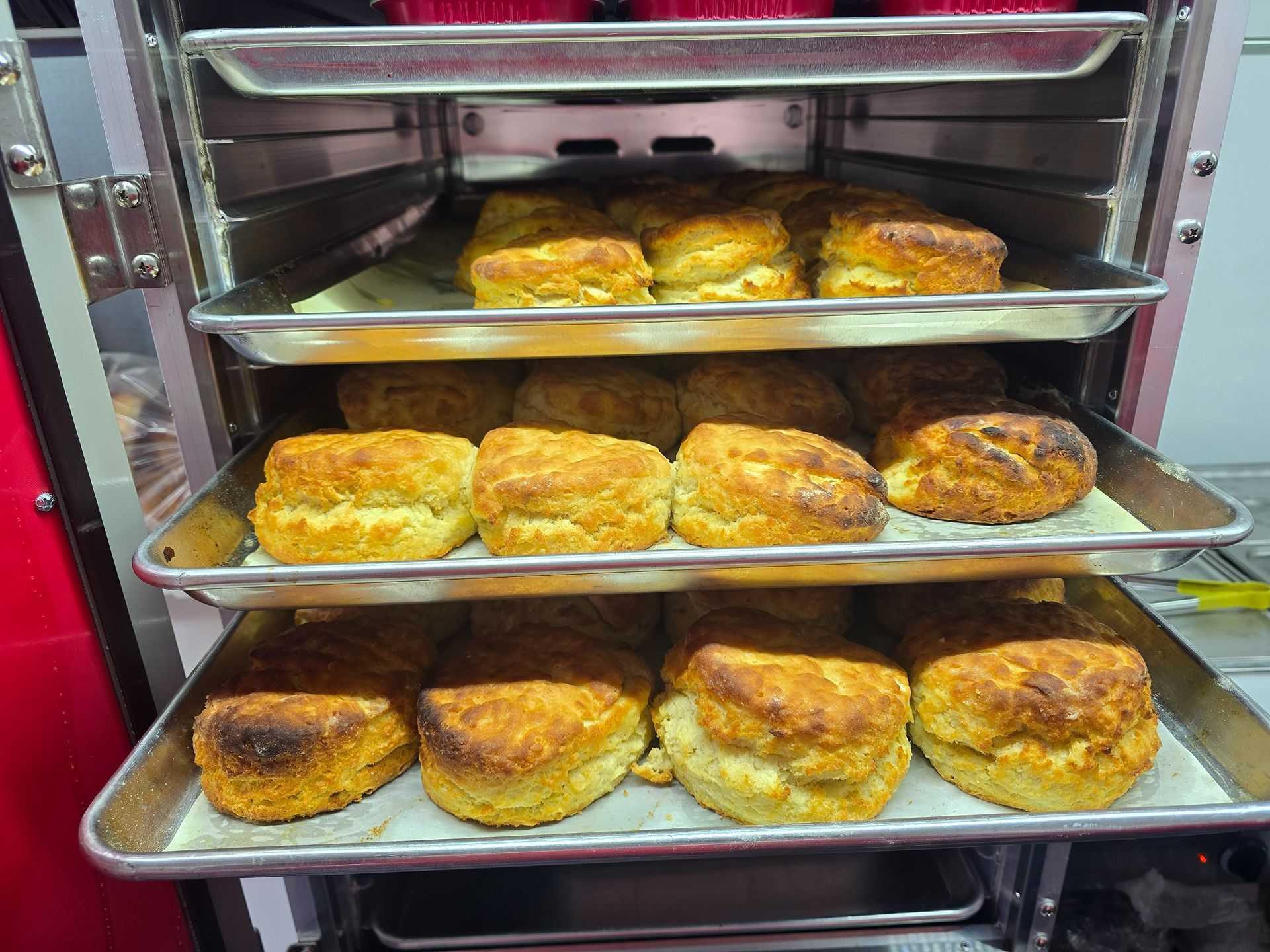 Tray racks filled with golden-brown baked pastries inside a commercial oven