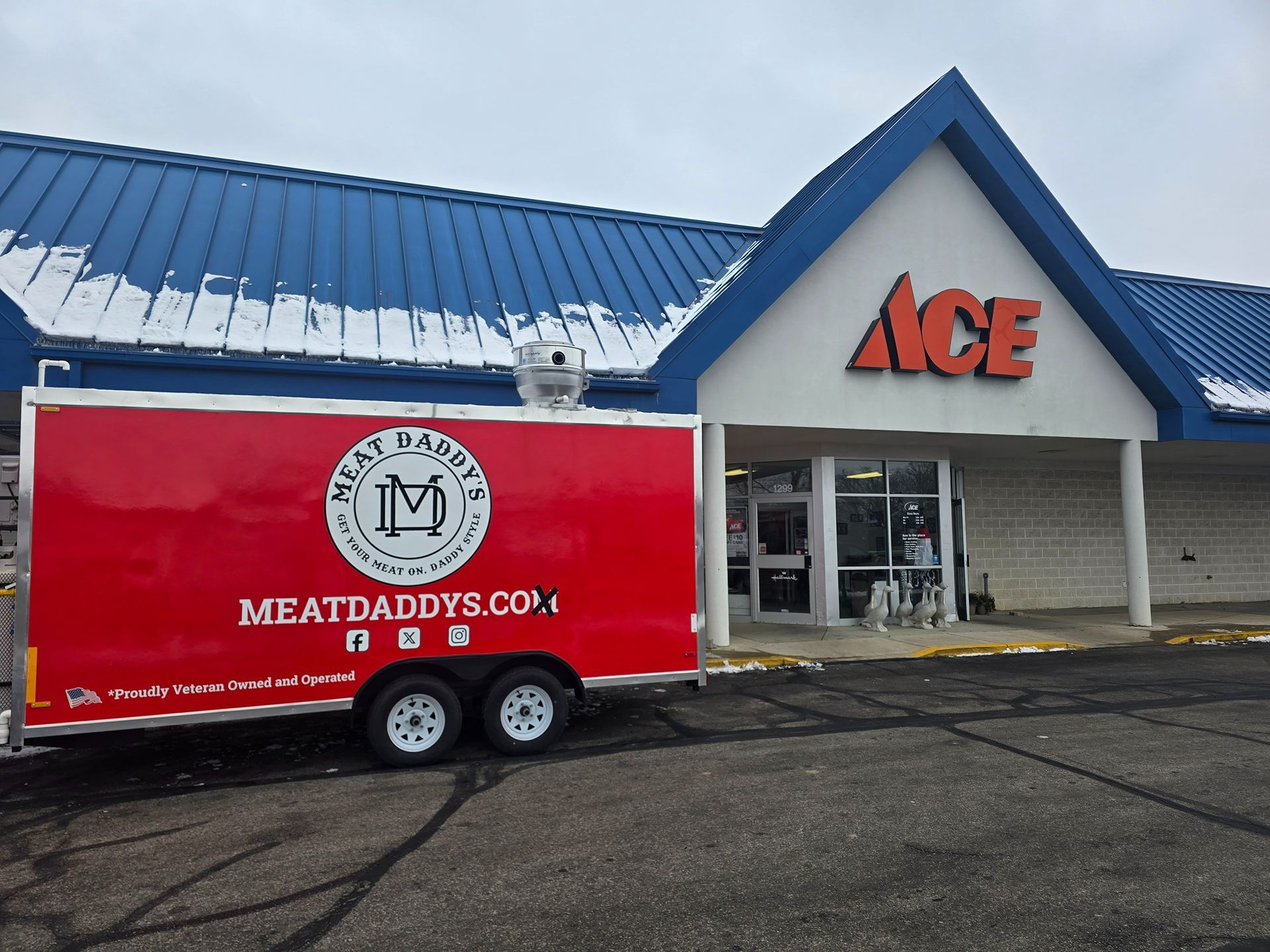 Red MeatDaddy's Co. trailer parked outside an ACE Hardware store with a blue roof.
