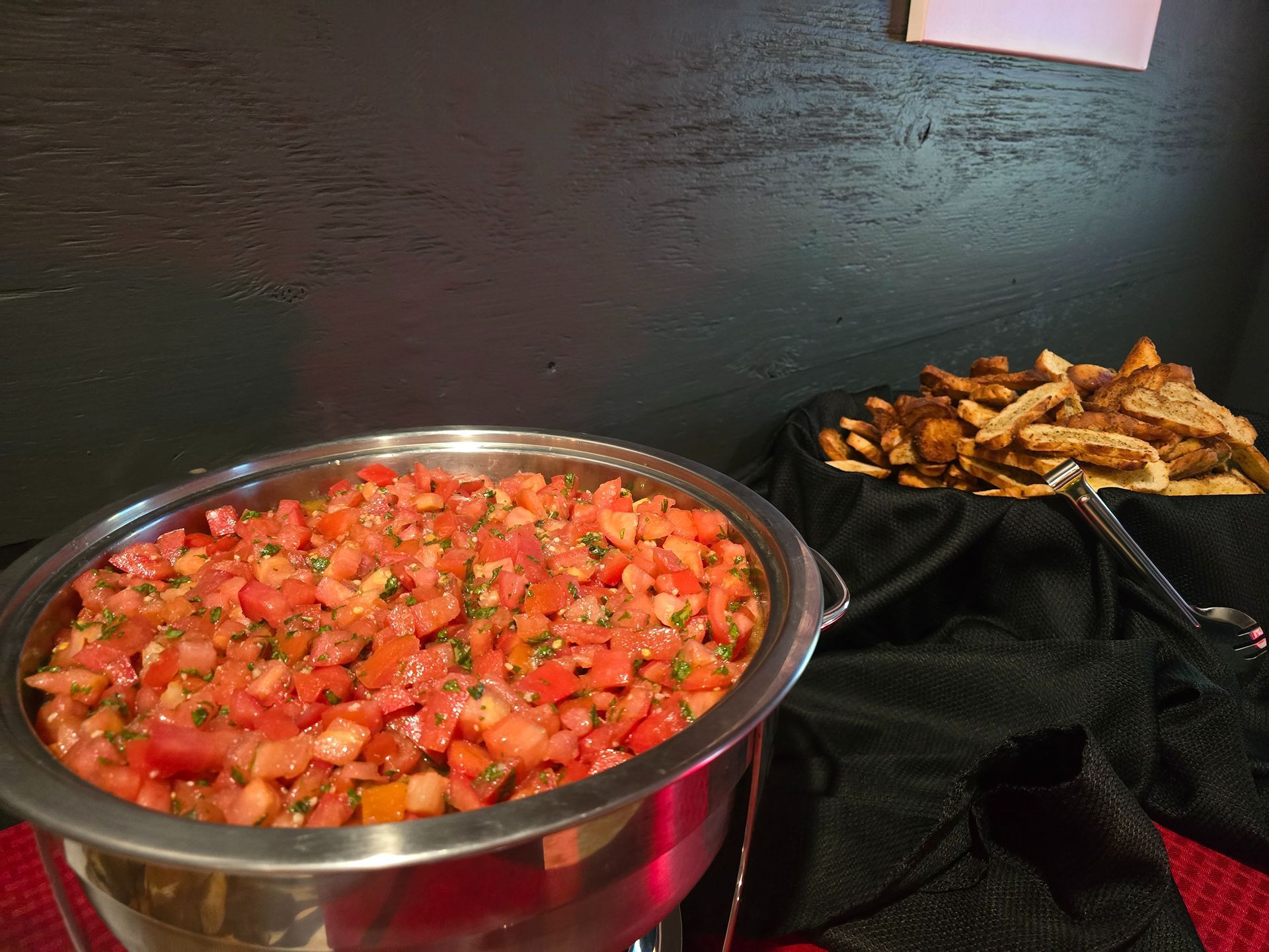 Bowl of diced tomato salsa beside a tray of fried snacks on a table