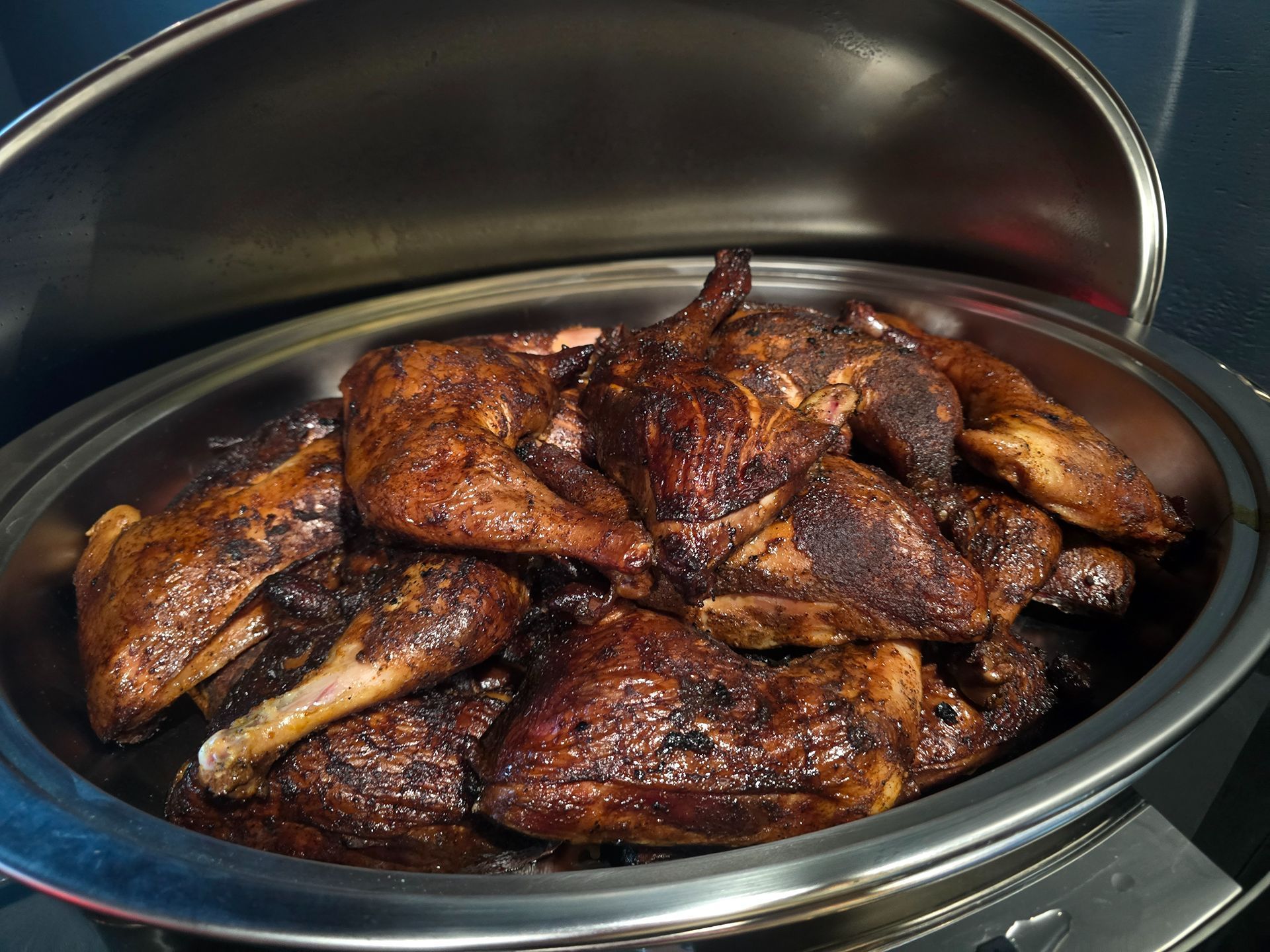 Grilled chicken wings piled in a black serving dish with a browned, charred glaze