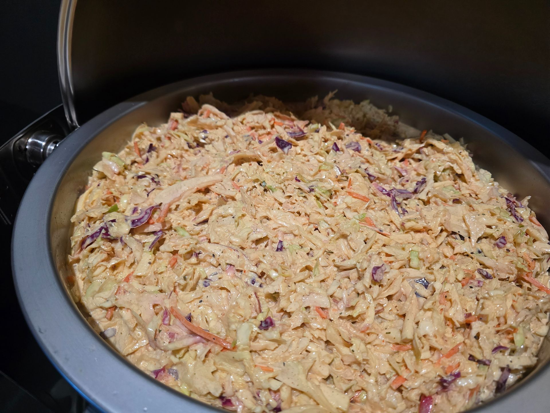A large pot filled with shredded cabbage slaw mixed with seasoning.