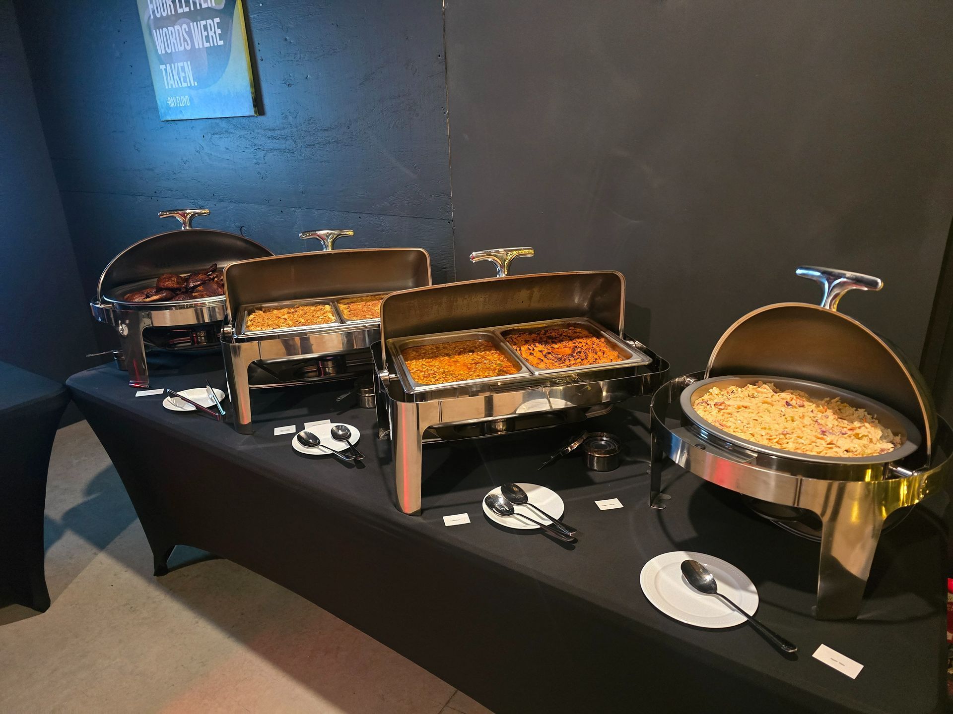 Buffet table with three covered chafing dishes of hot food in a dimly lit room