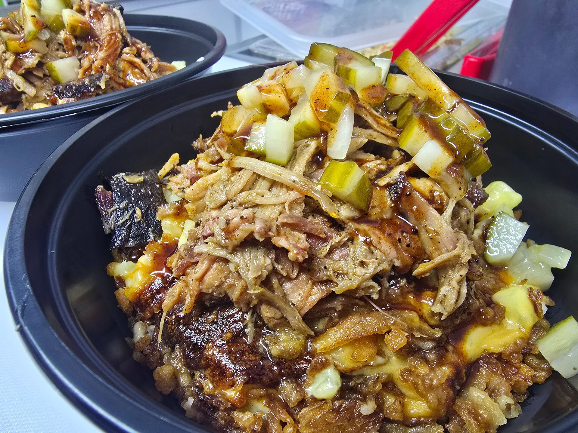 Two bowls of grilled meat topped with diced onions and sauce on a table