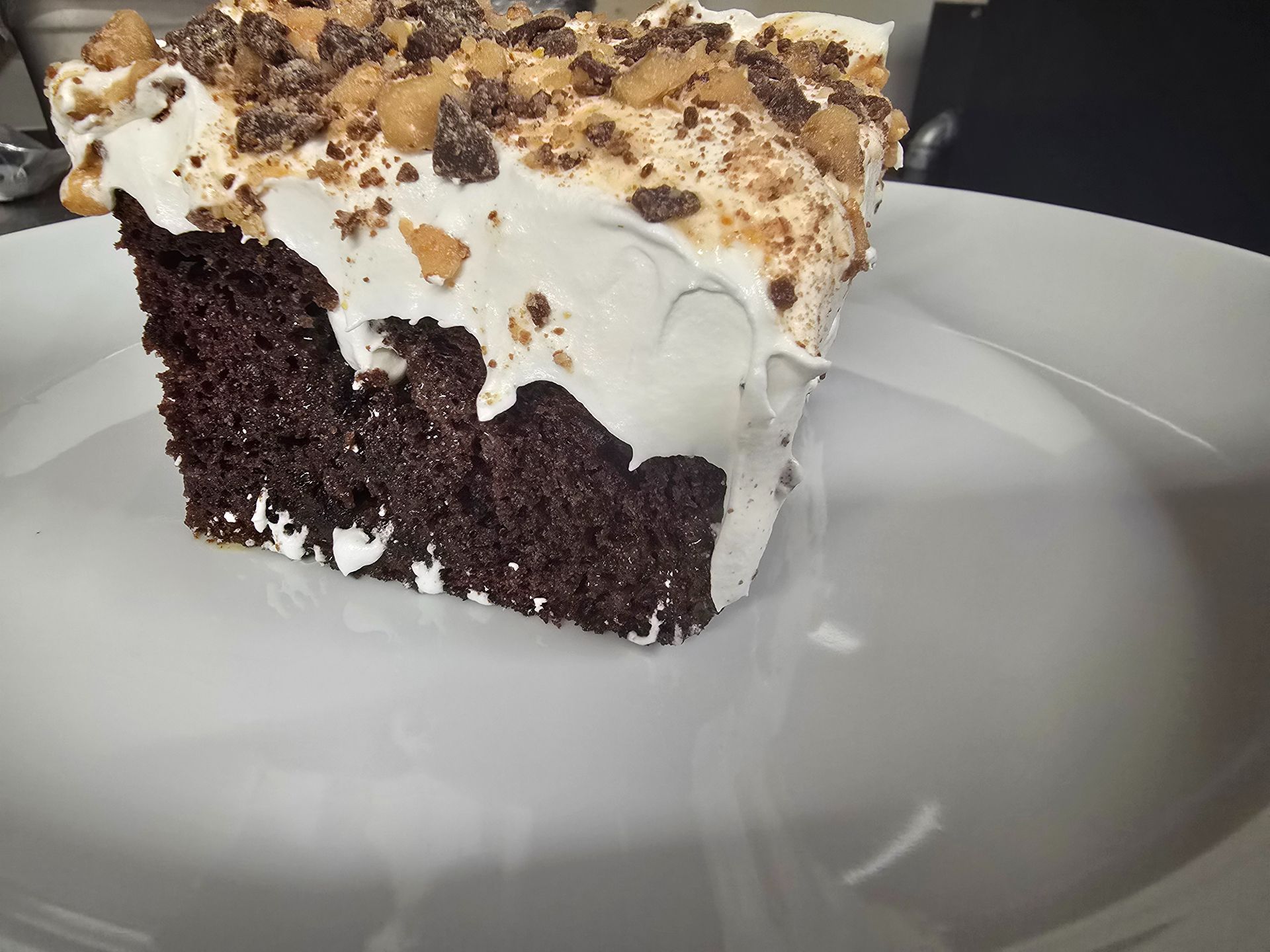 Slice of chocolate cake with white frosting and crumb topping on a white plate