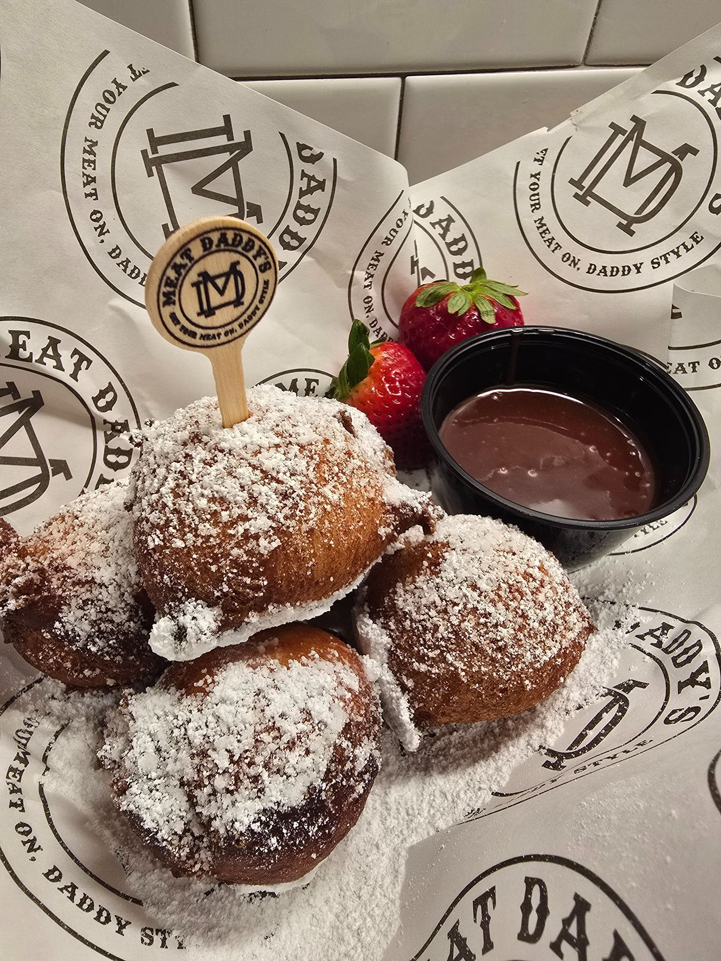 Powdered sugar doughnuts with strawberry sauce on a branded dessert plate