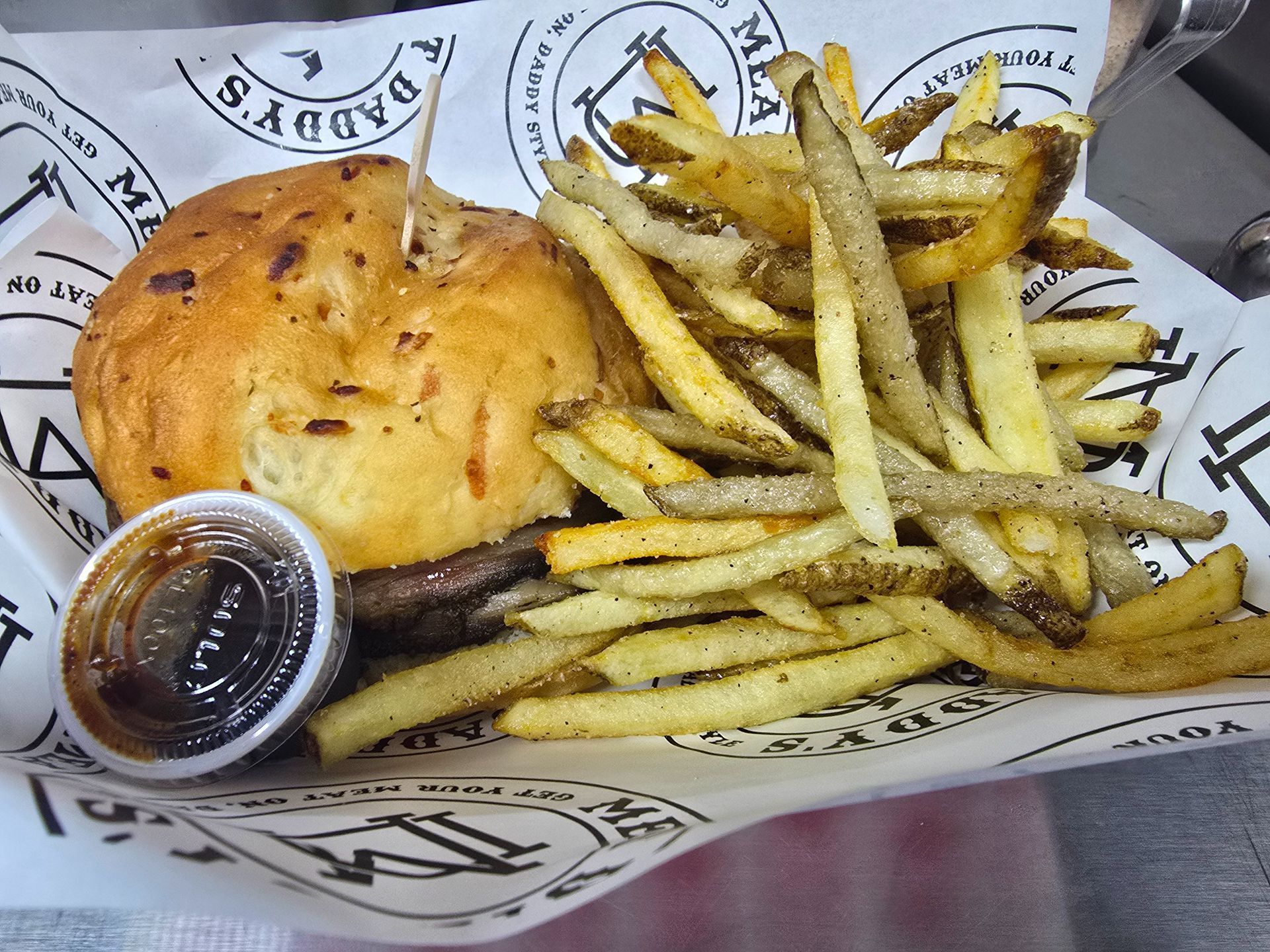 Burger and fries in a basket with a small cup of dipping sauce