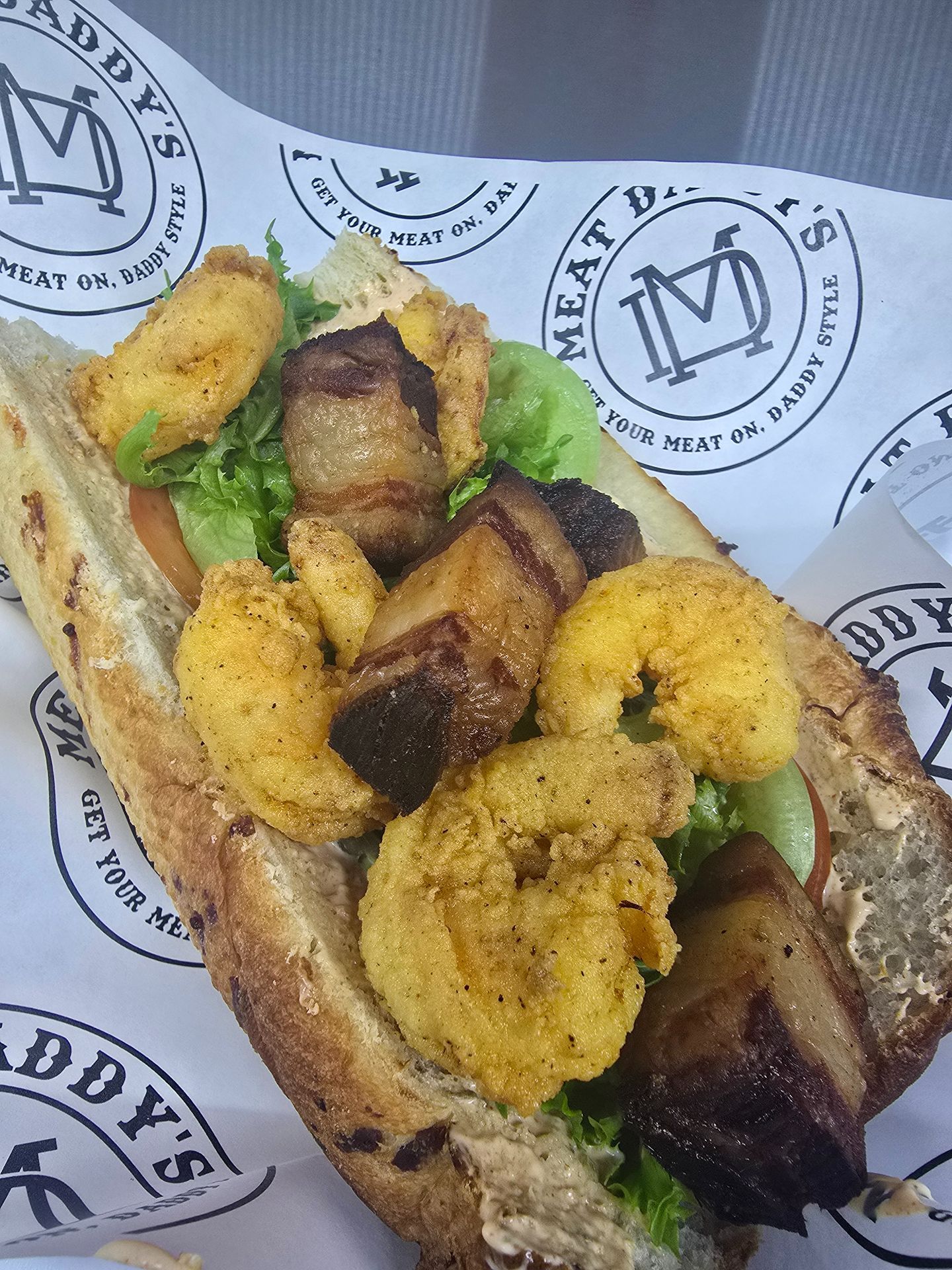 Grilled shrimp and vegetables in a bread bowl on branded paper wrapping