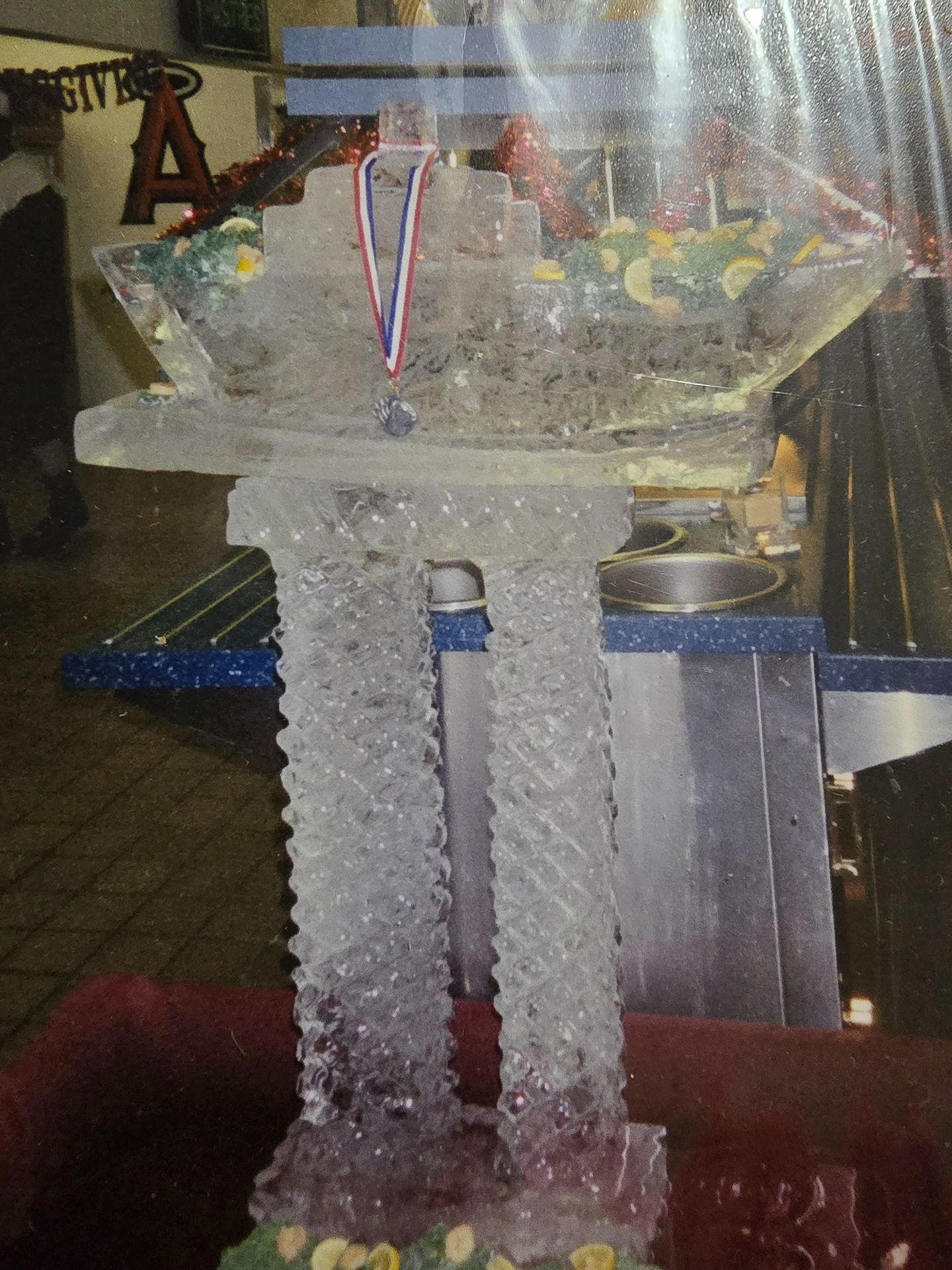 Ice sculpture on a table, decorated with a medal and blue-white ribbons at an event