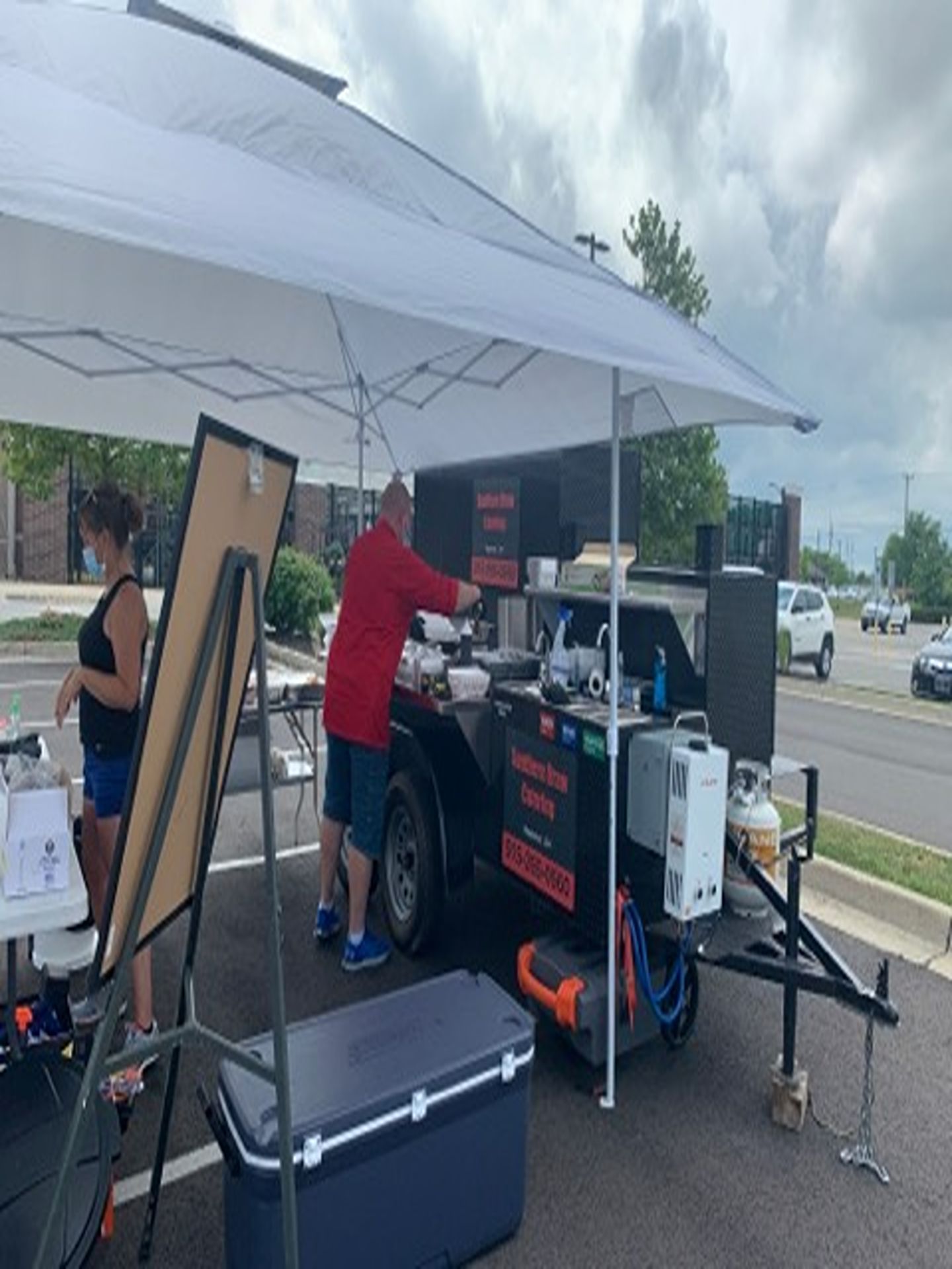 Outdoor coffee cart under a white canopy with a vendor serving drinks by the roadside