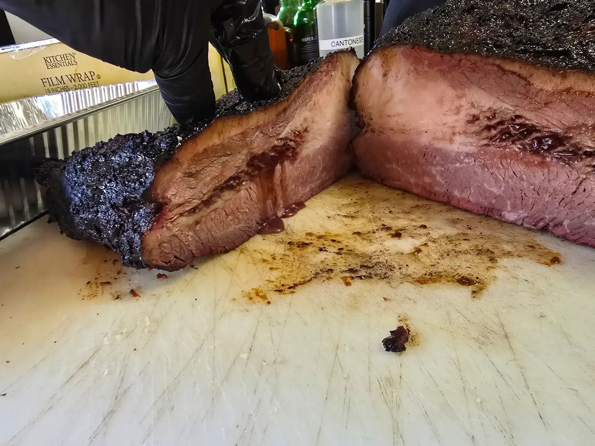 Close-up of sliced smoked brisket on a cutting board, with dark bark and pink smoke ring