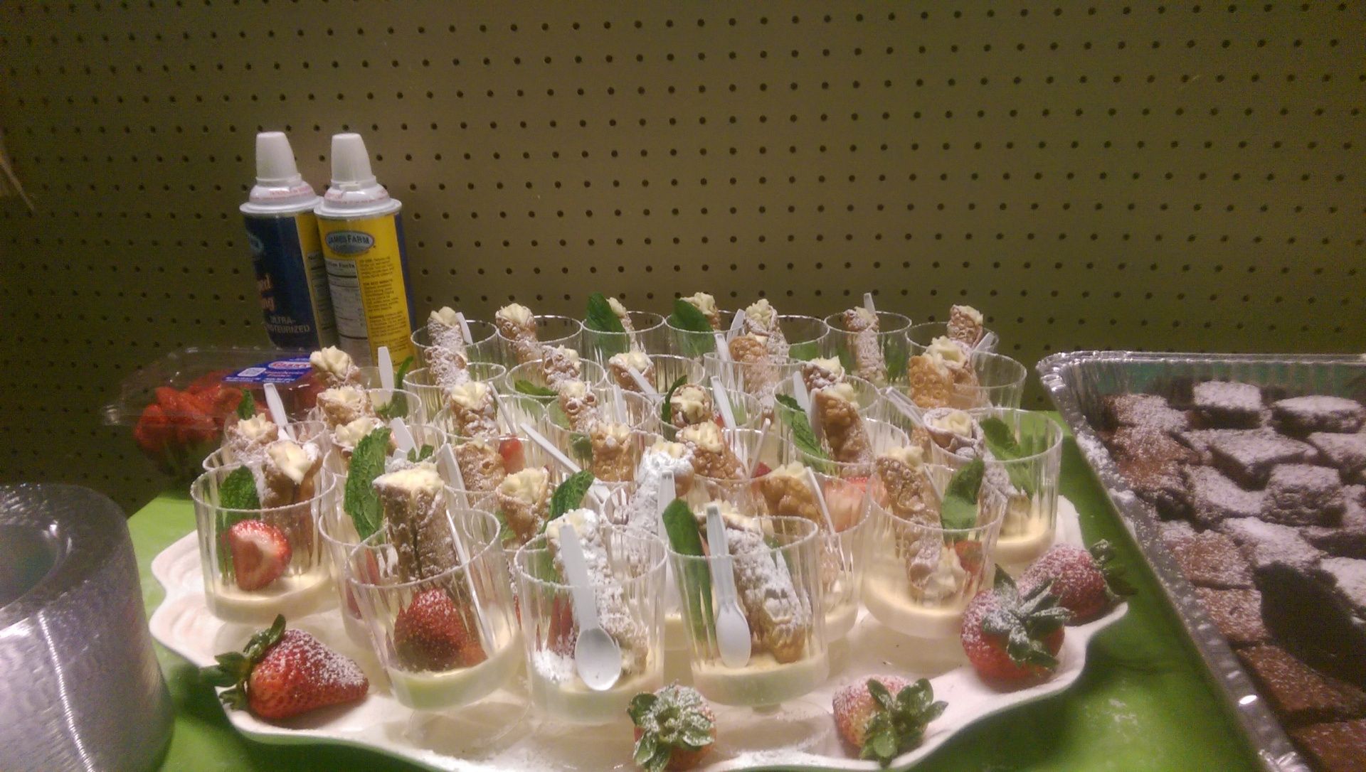 Tray of individually wrapped candy treats in small cups on a table with yellow drink bottles in the background