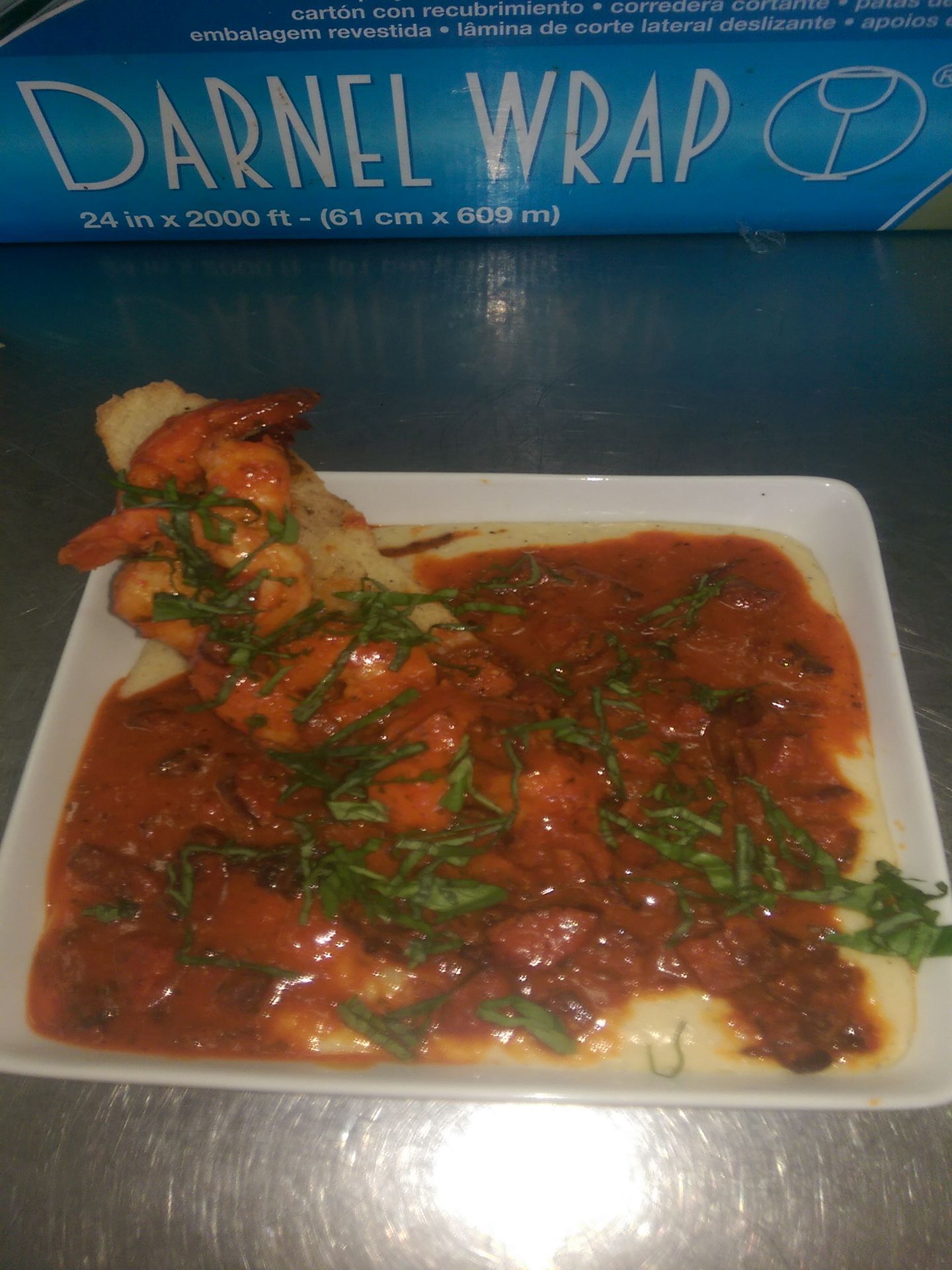 Takeout box of saucy dark red wrap with herbs on a white plate, labeled “Darnel Wrap”