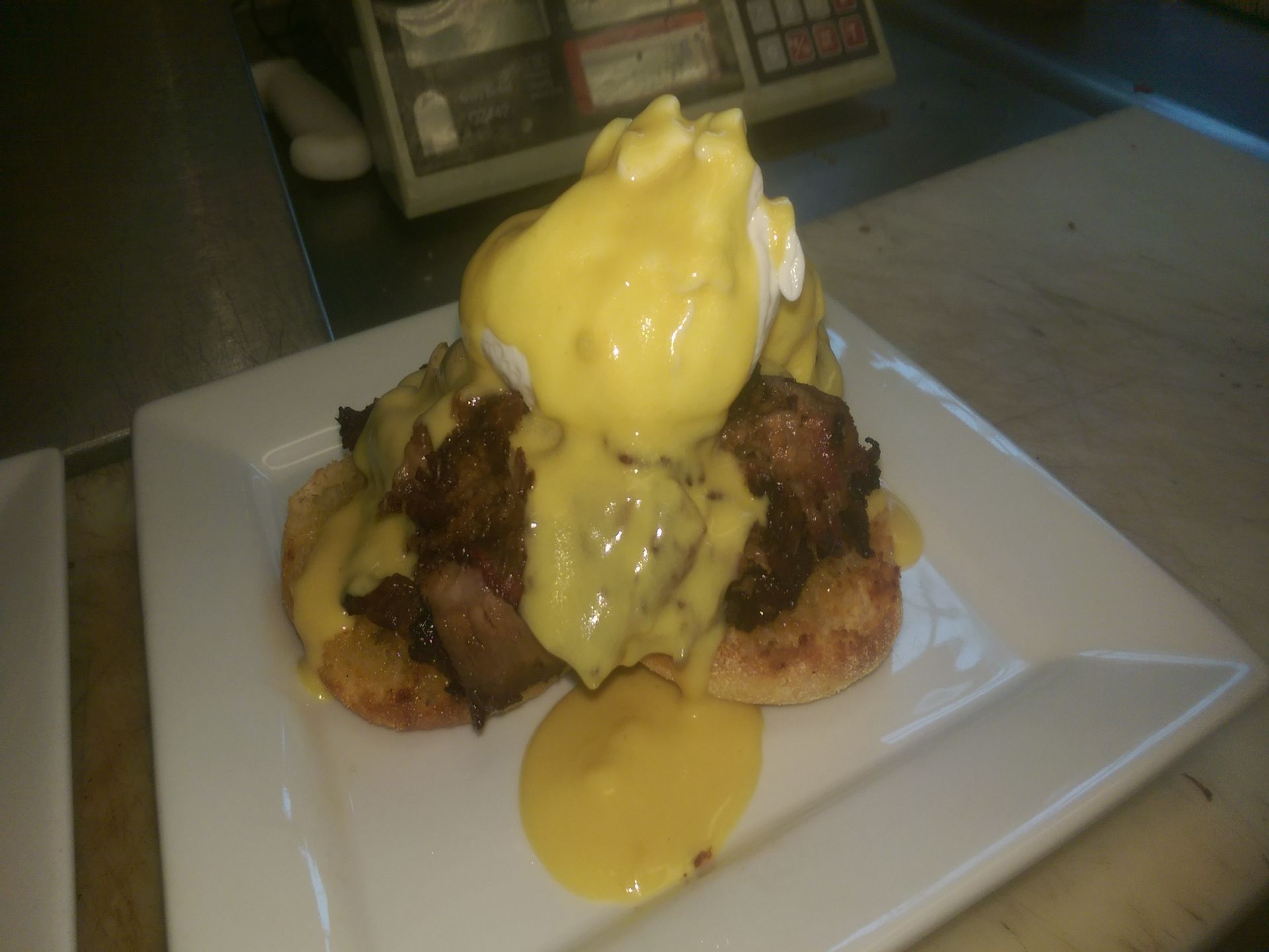 Dessert topped with yellow sauce on a white plate in a dimly lit setting