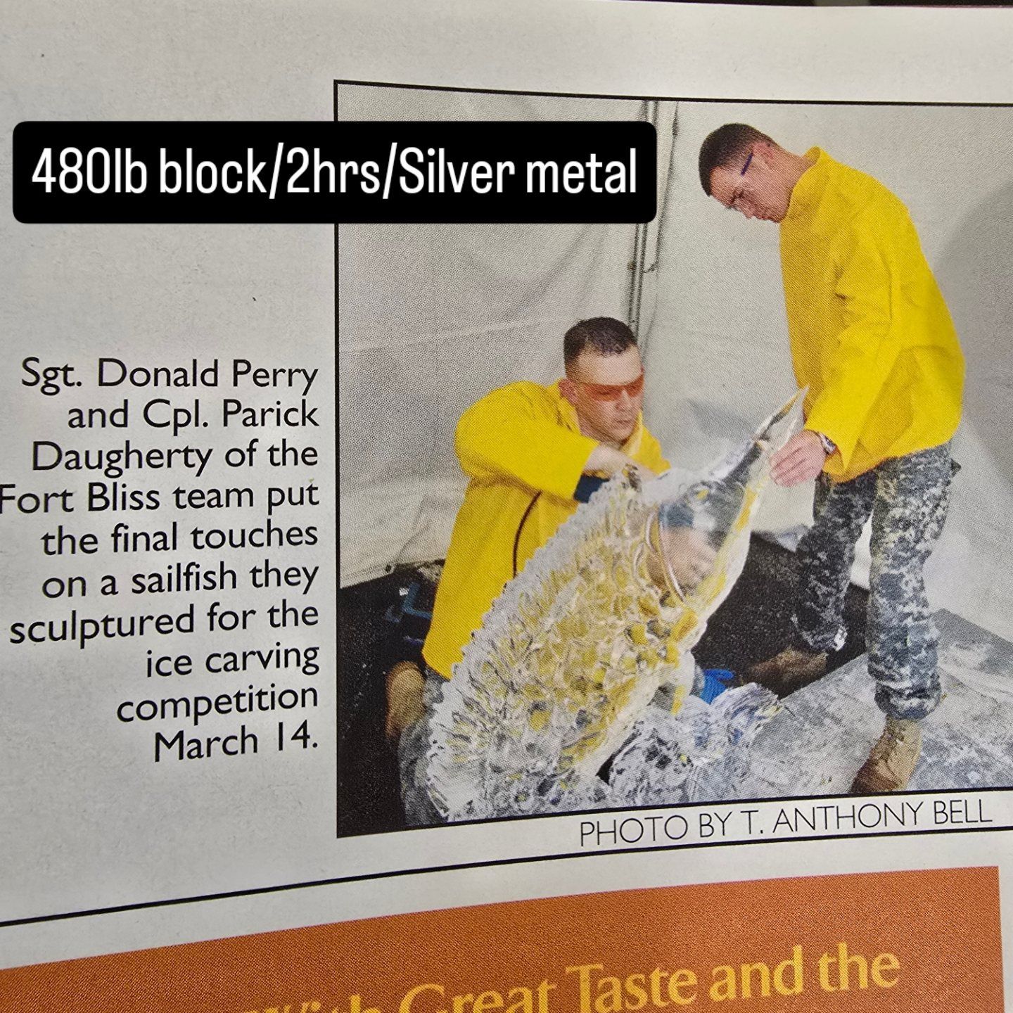 Two people in yellow jackets carving a large silver ice block with tools outdoors