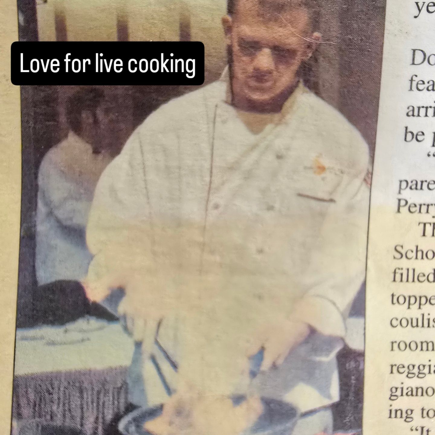Chef cooking at a live event, wearing a white coat and stirring food at a table