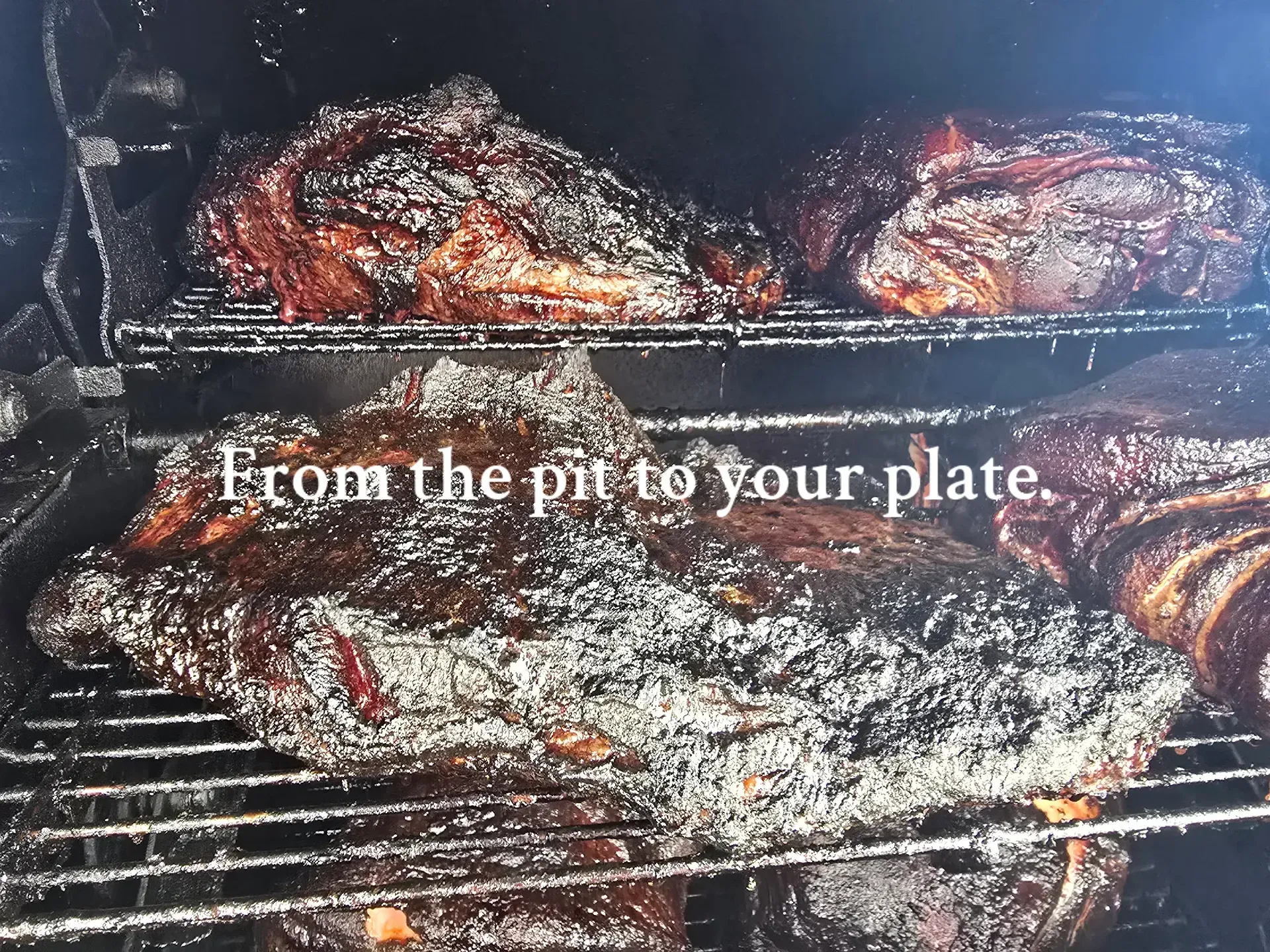 Charcoal grill with sizzling meat and text, “From the pit to your plate.”