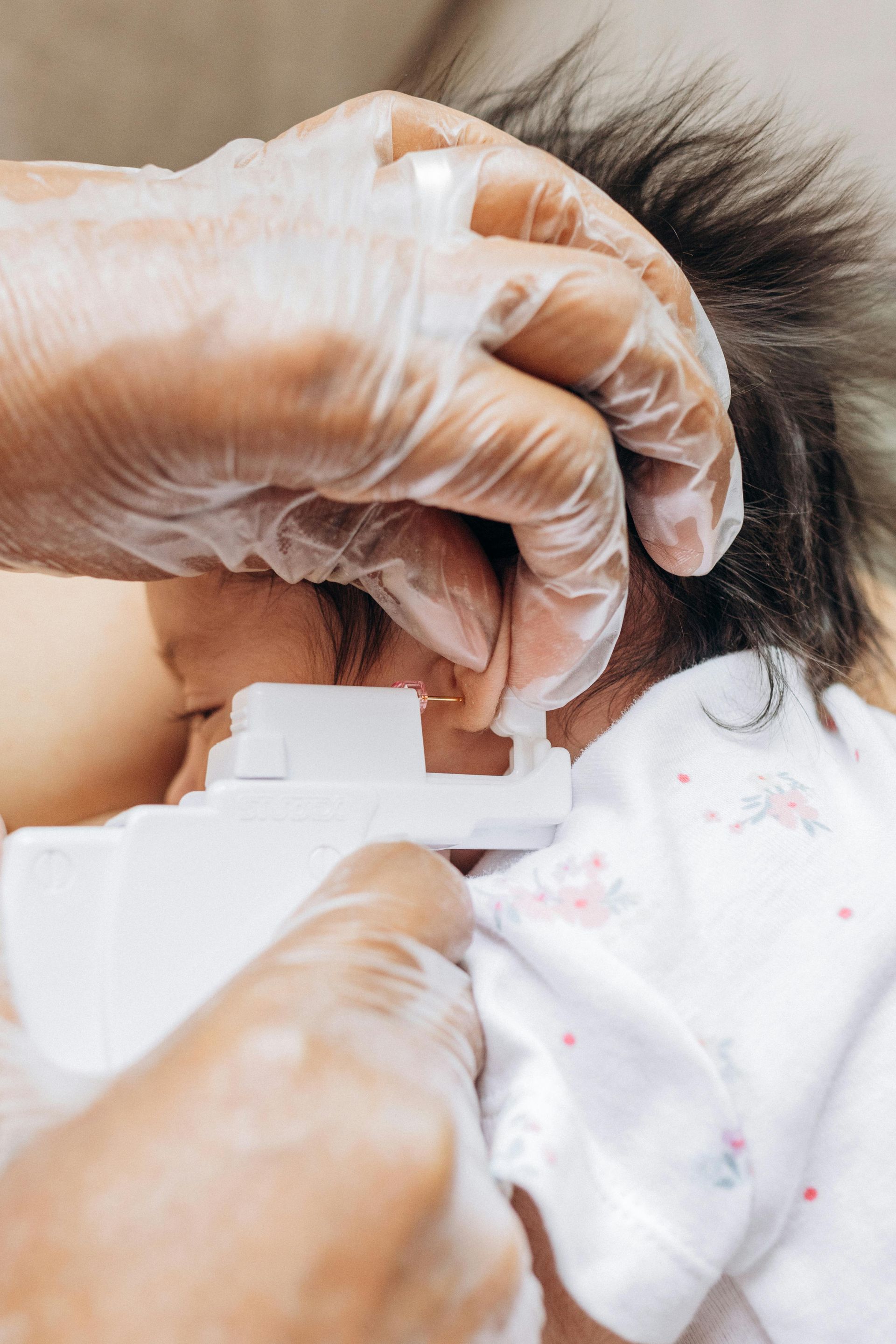 Gloved hands apply drops to a child’s eye with a small bottle