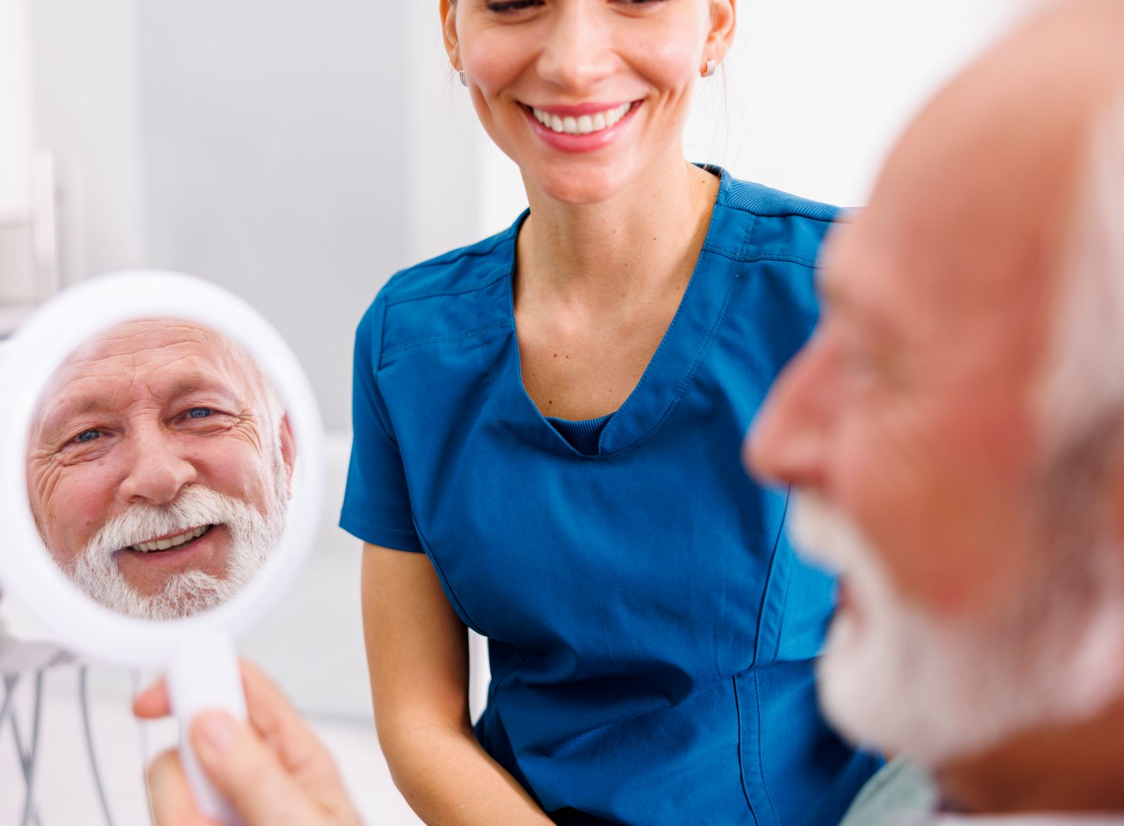 A dentist is holding a tooth color chart in front of a woman 's mouth.