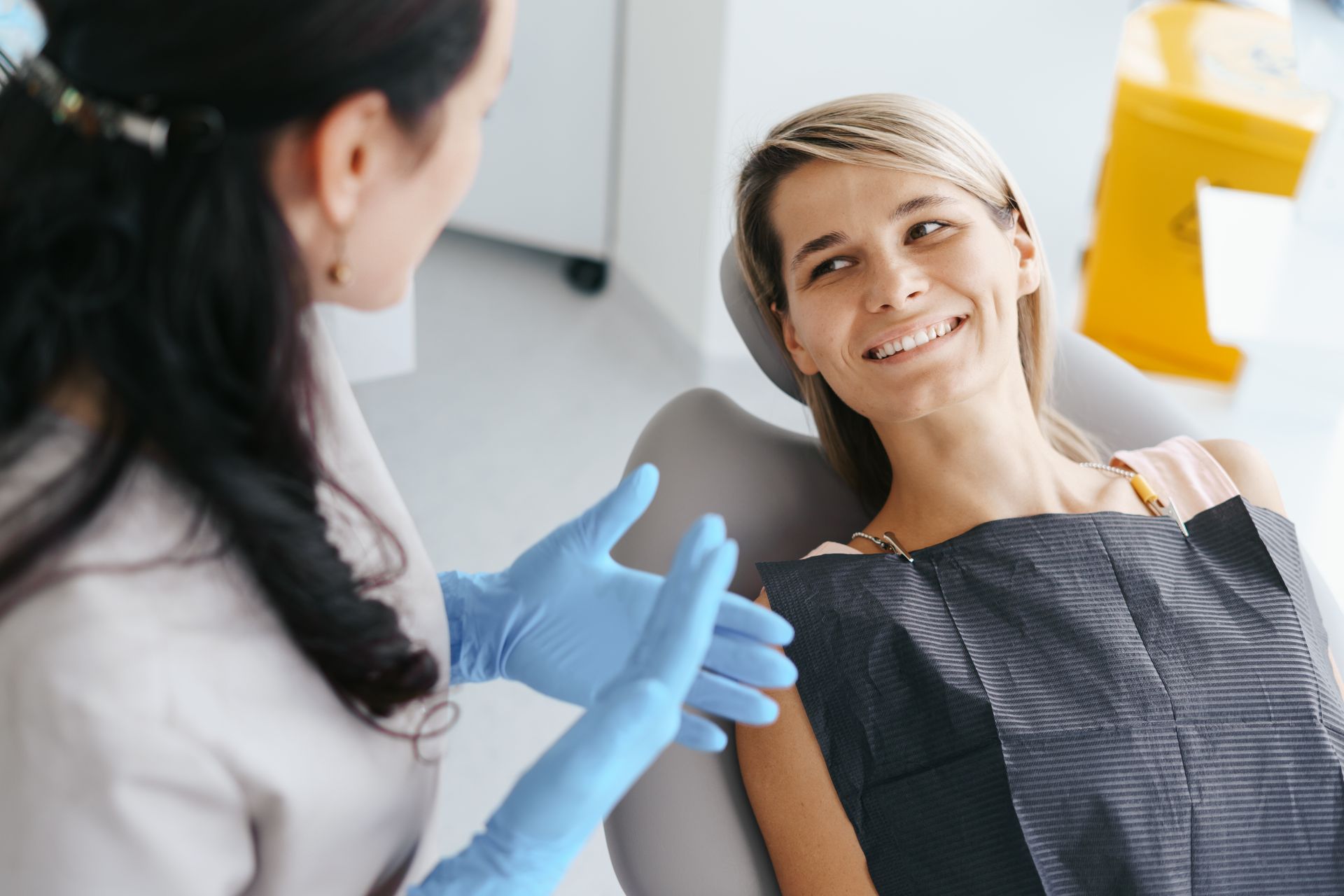 A woman is sitting in a dental chair talking to a dentist.