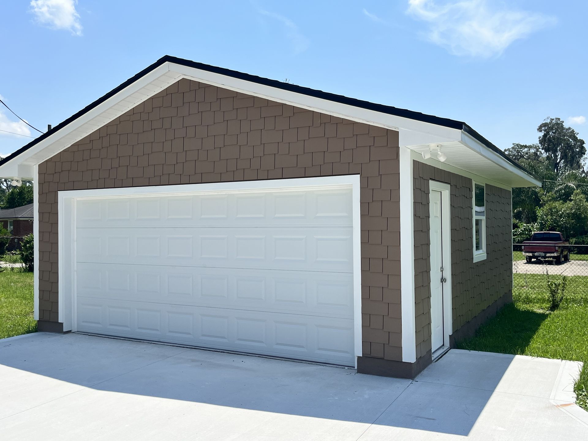 Single-car garage with white door and tan siding on a sunny day