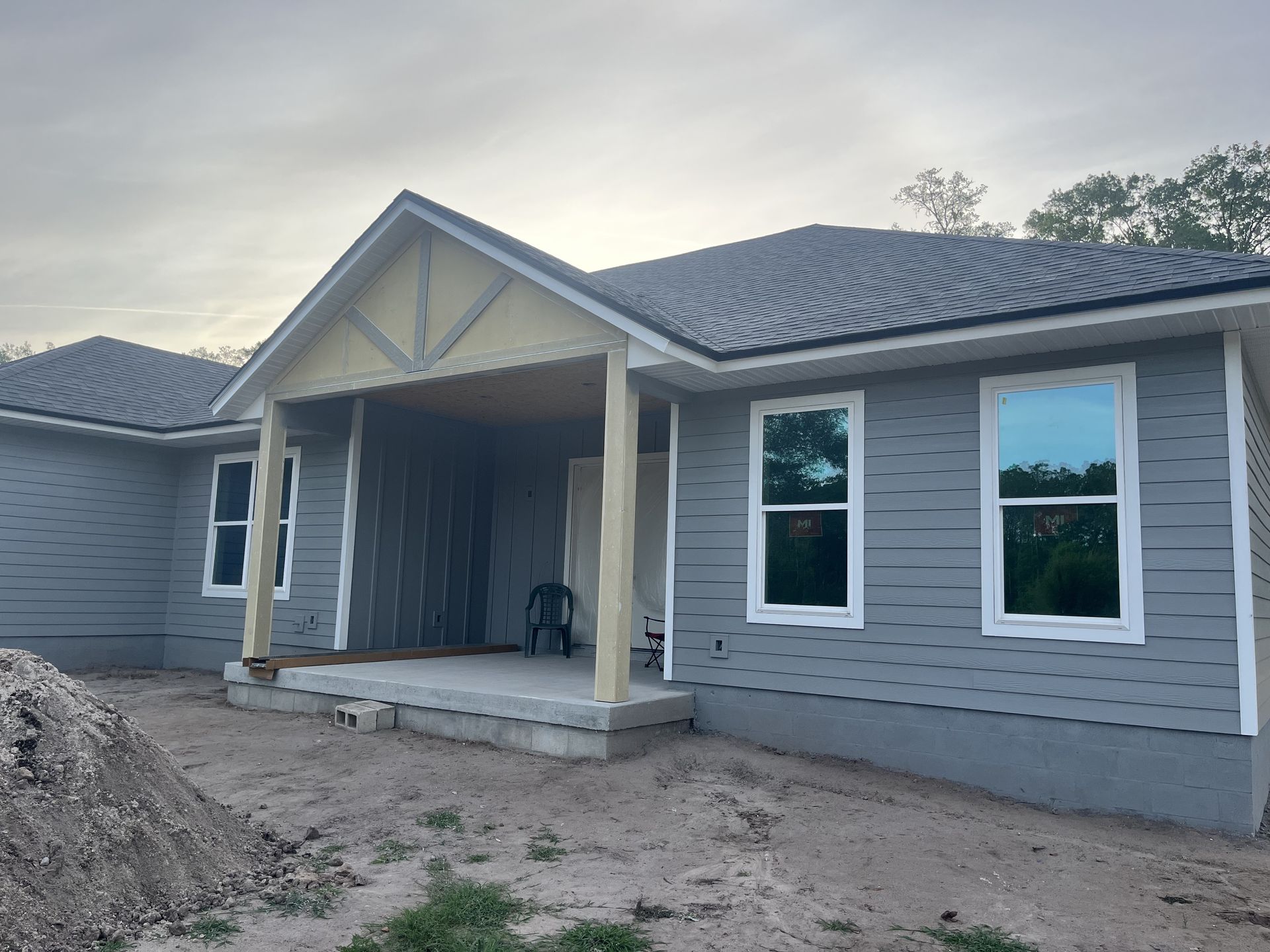 New house exterior with gray siding, white trim, and a covered front porch under construction