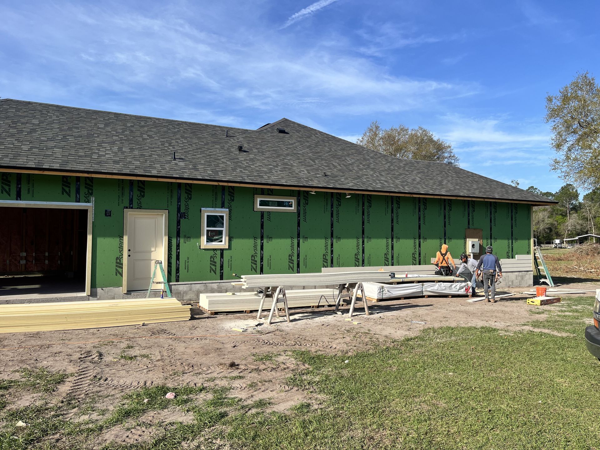 Green building with benches and a few people outside under a blue sky