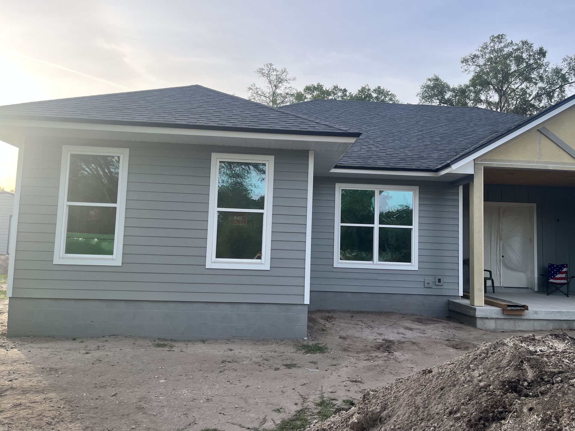 New gray single-story house under construction with unfinished yard and front porch