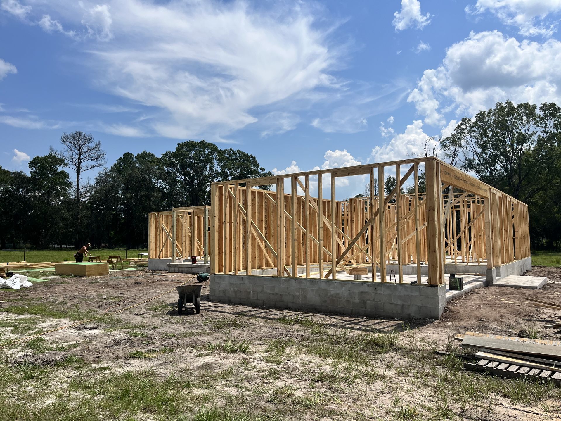 Wood-framed house under construction on a concrete slab under a partly cloudy sky