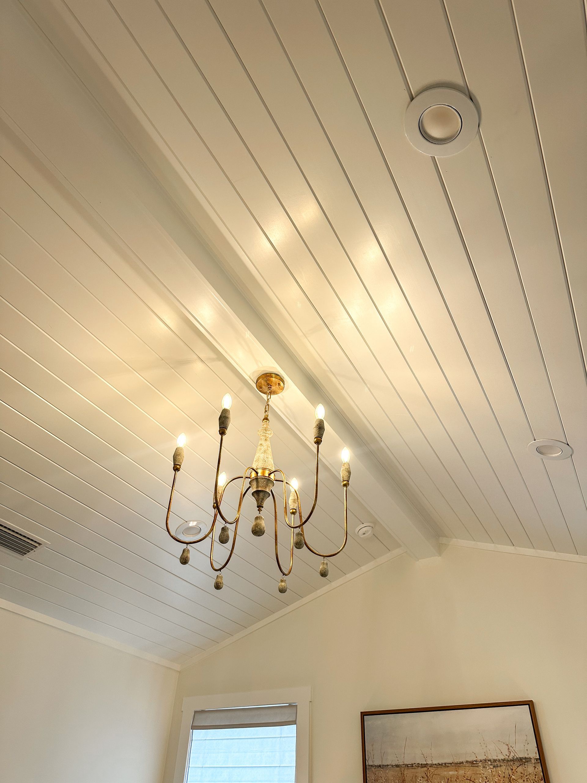 White paneled ceiling with a brass chandelier in a bright room