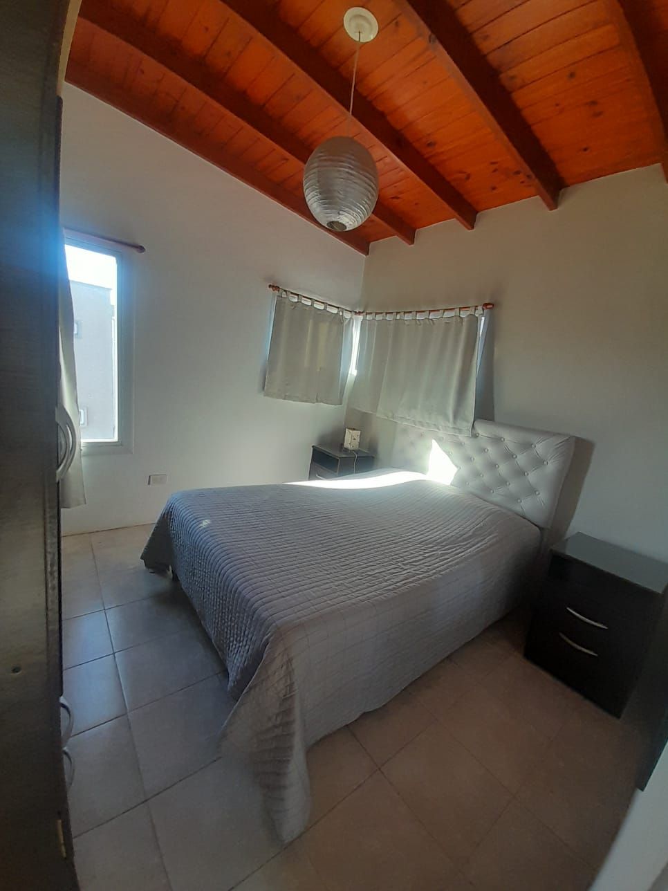 Interior de una habitación con techo de madera, ventanas, un sofá y vista al exterior.