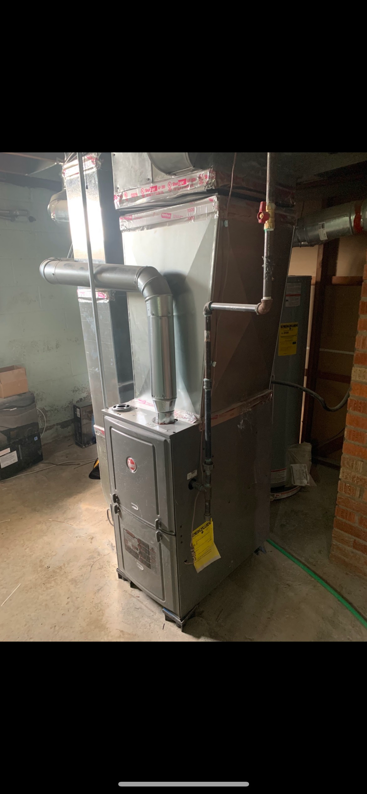 Furnace and air handler system in a basement, metal ducts, yellow energy label.