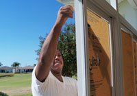 Man covering windows — Leesburg, FL — Aluminum Contractors Inc