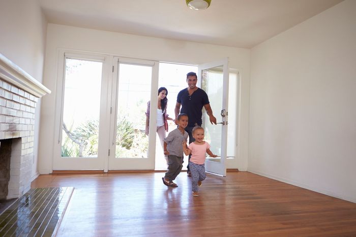 A family is walking through an empty living room in their new home