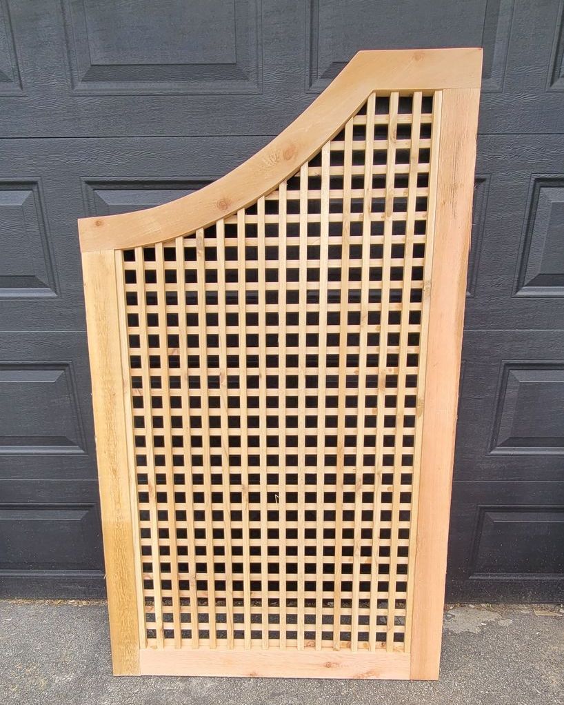 A wooden lattice is sitting in front of a black garage door