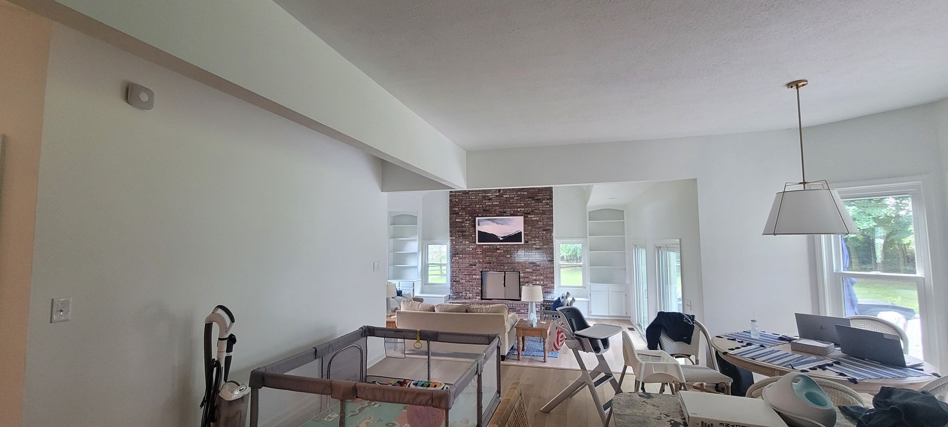 A living room with white walls and a brick fireplace