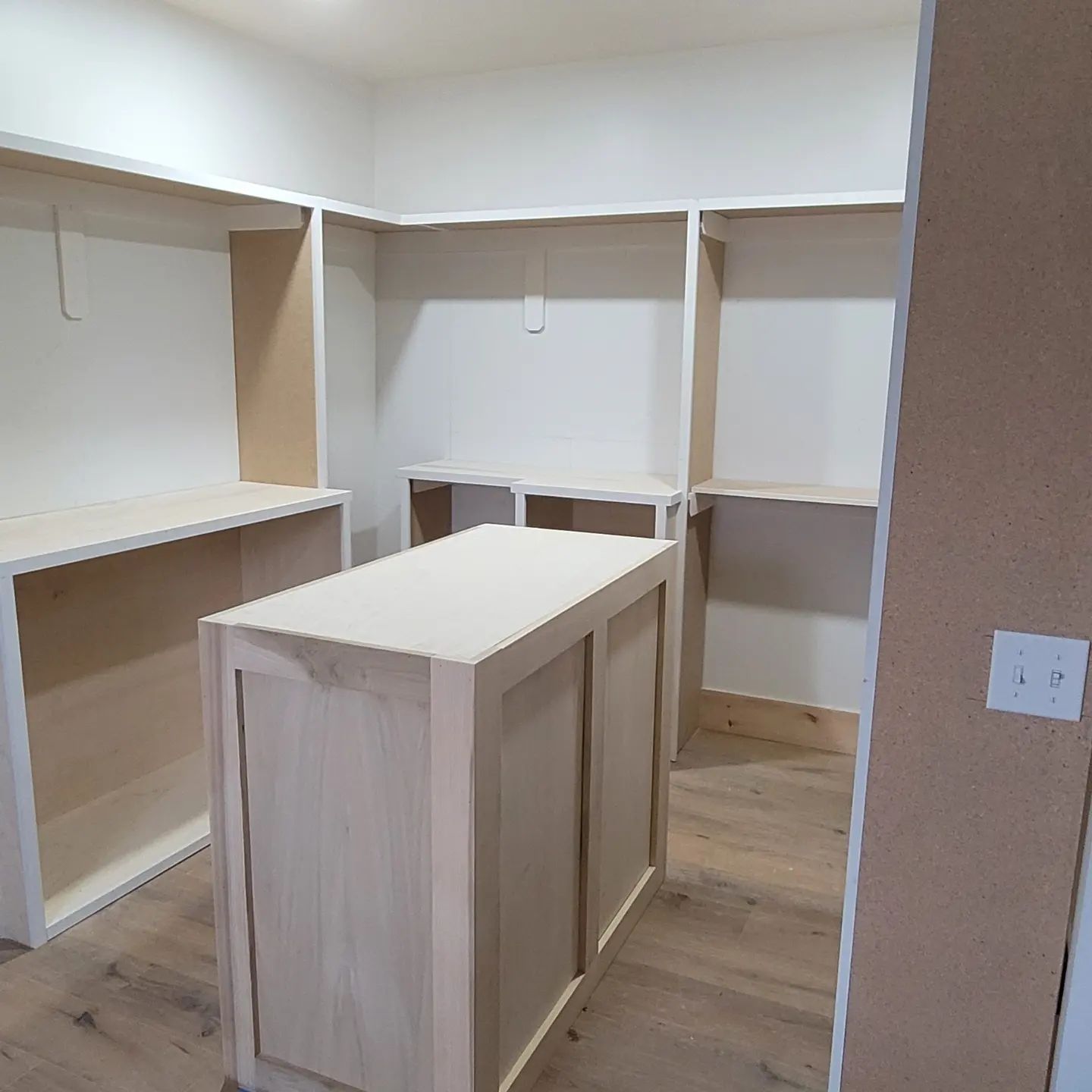 A walk in closet with a large wooden island in the middle .