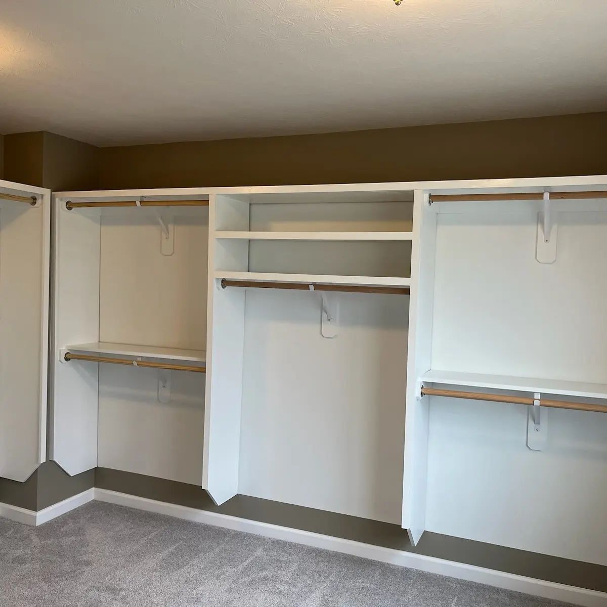 A closet with a lot of shelves and hanging clothes .