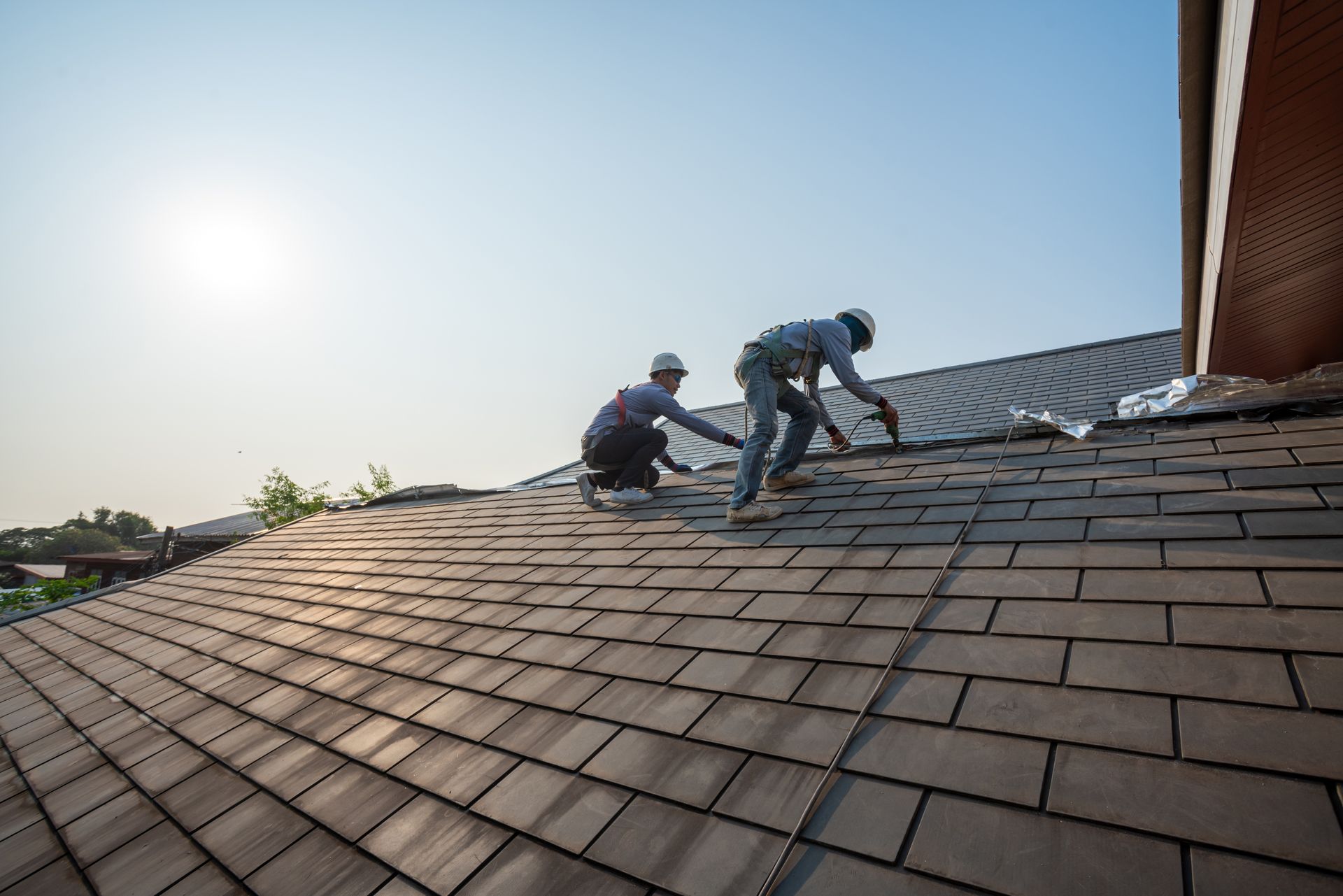 A roofer is using a pneumatic gun to repair the top of a roof.