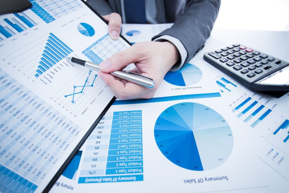 Person in Suit Points at Financial Charts With a Pen Next to a Calculator — Blue Chip Bookkeeping in Mackay, QLD