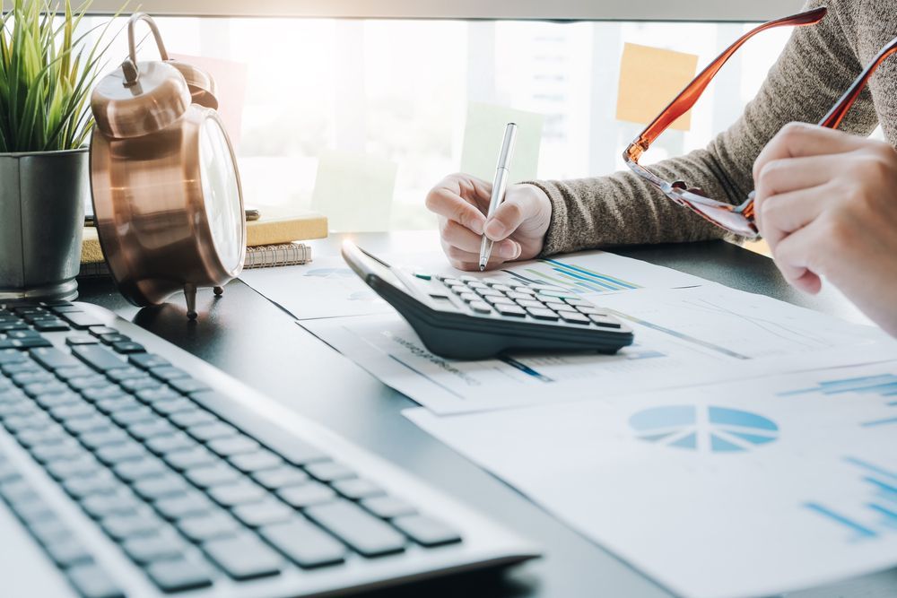 A Person Is Sitting At A Desk With A Calculator And A Pen — Blue Chip Bookkeeping In Nome, QLD