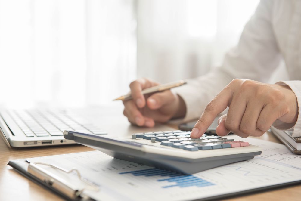 Person Calculating Figures With Calculator, Pen, and Laptop on a Desk — Blue Chip Bookkeeping in Cairns, QLD