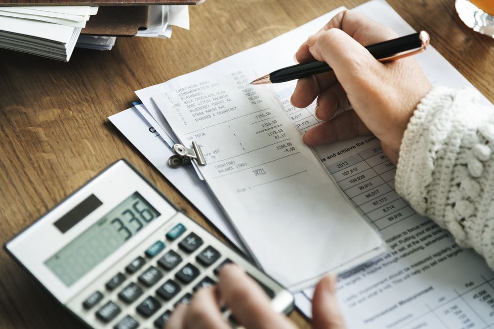 Person Calculating Finances With a Calculator and Paperwork — Blue Chip Bookkeeping in Cairns, QLD