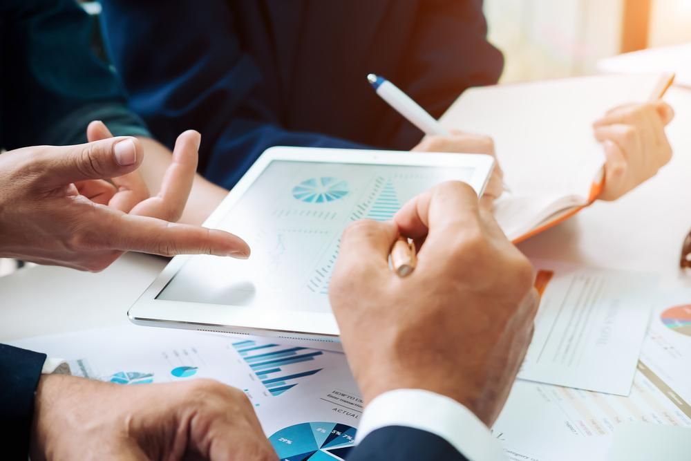 Man Analyzing The Graph In The Laptop And Mobile Phone — Blue Chip Bookkeeping In Maitland, QLD