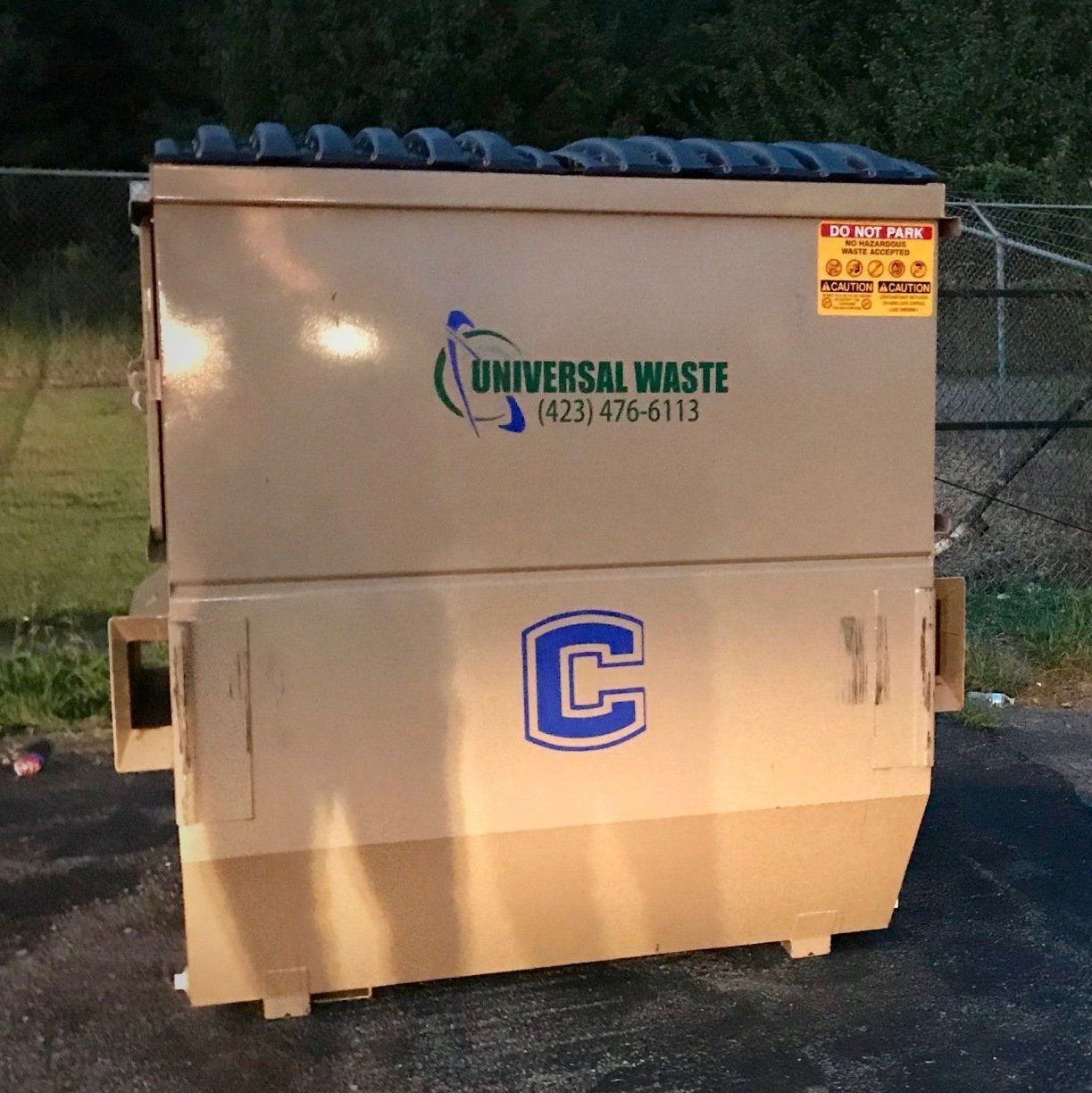 A brown dumpster that says universal waste on it